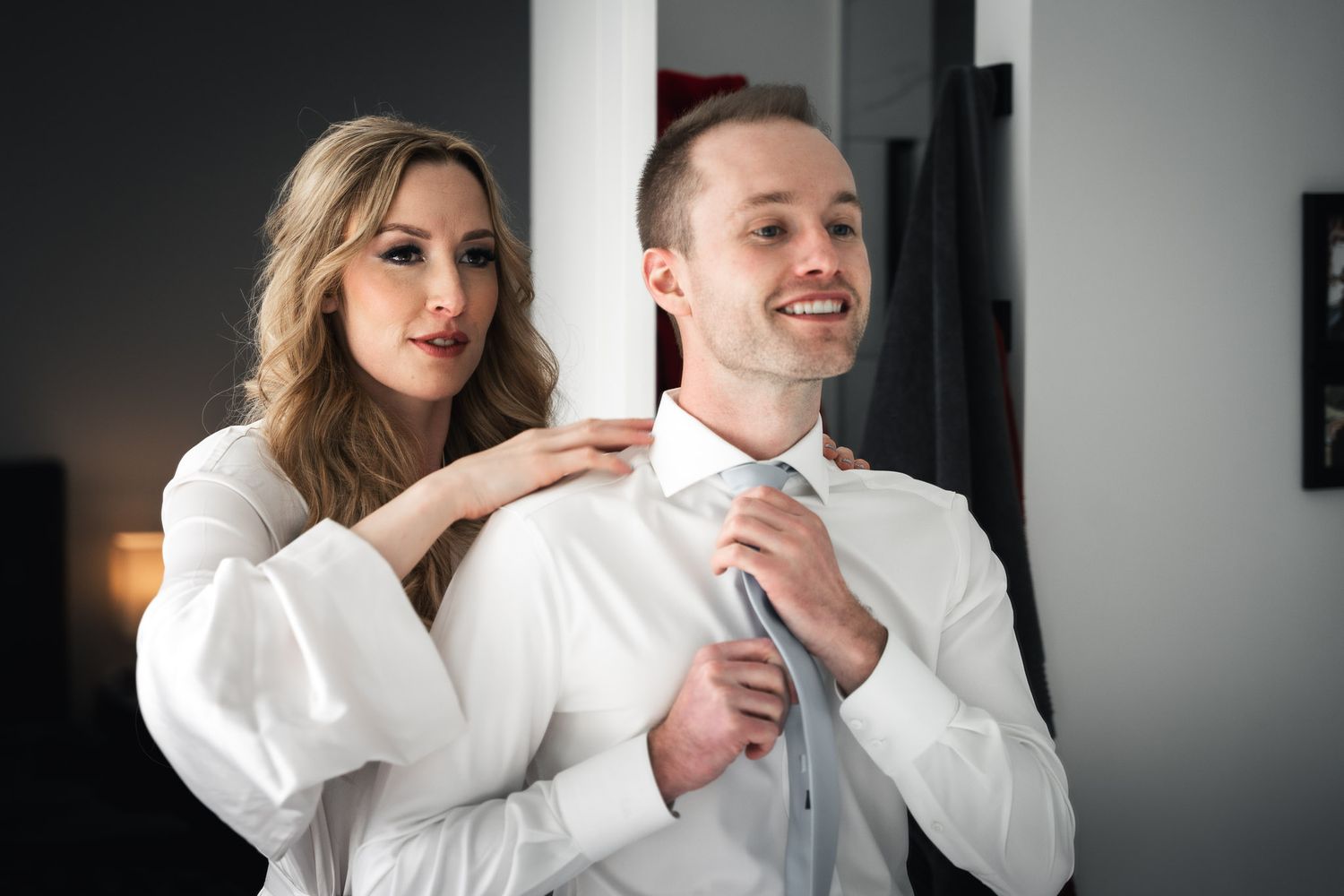 Intimate getting ready moments captured in black and white with white button-down shirts.