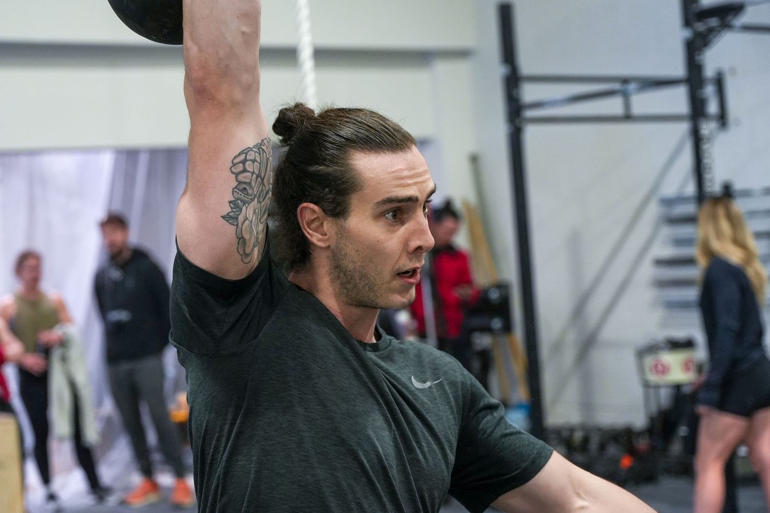 Athletes practicing weightlifting techniques in a CrossFit gym environment.