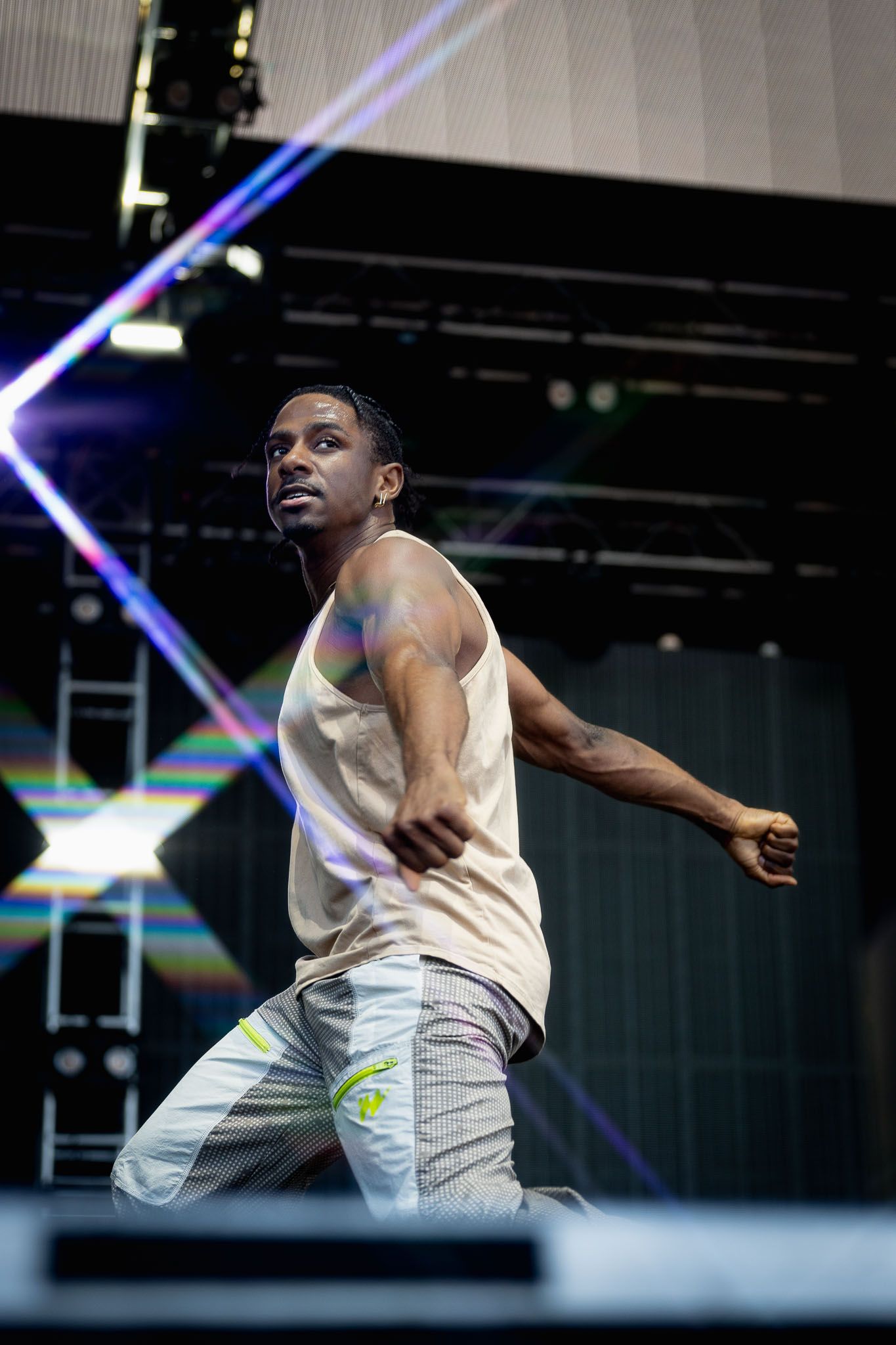 Performer in white outfit executes dynamic dance moves on illuminated stage.