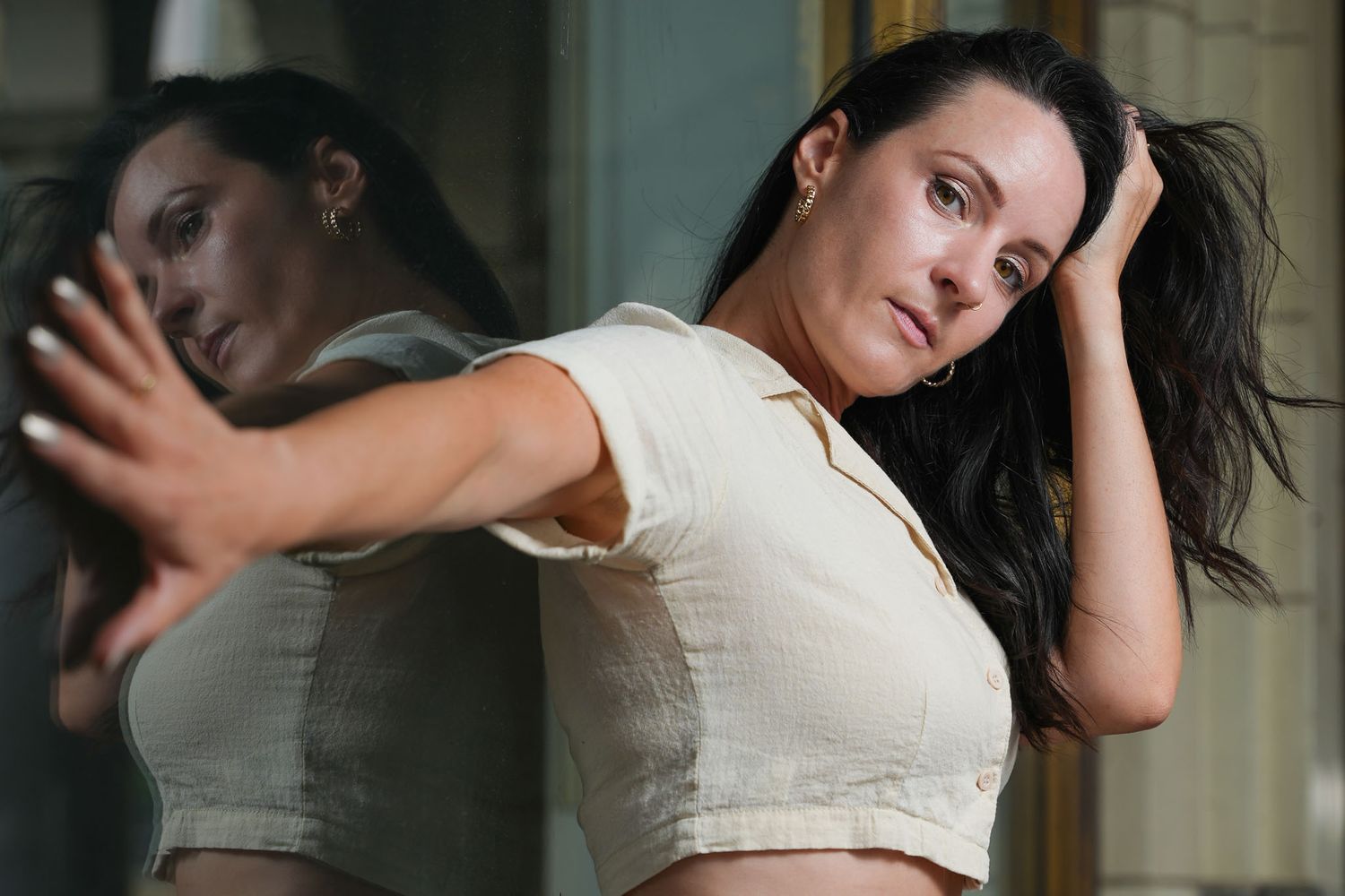 Dancer executes graceful movements in cream colored top against architectural setting.