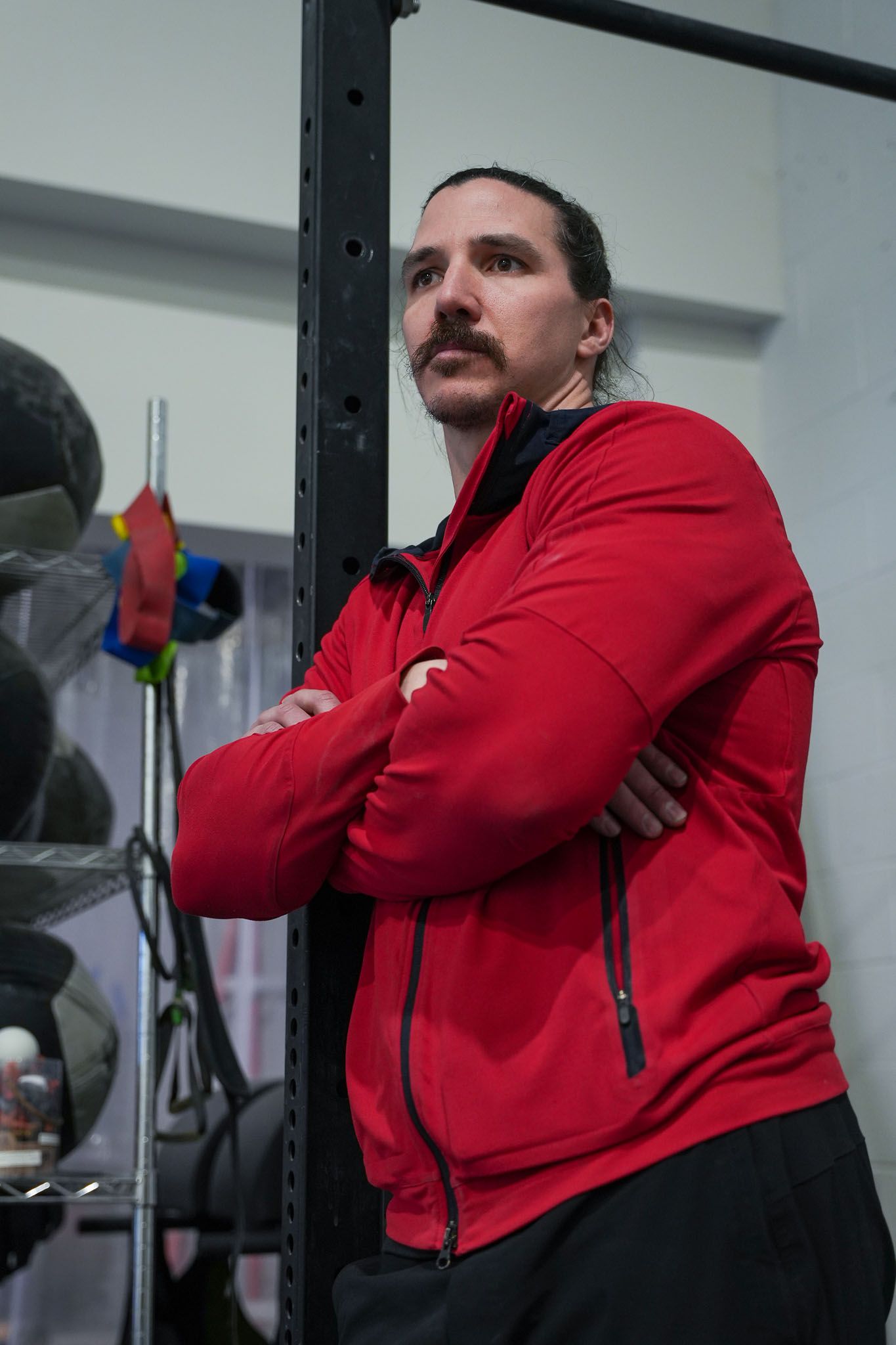 Person in red jacket demonstrating various stretching positions in gym.
