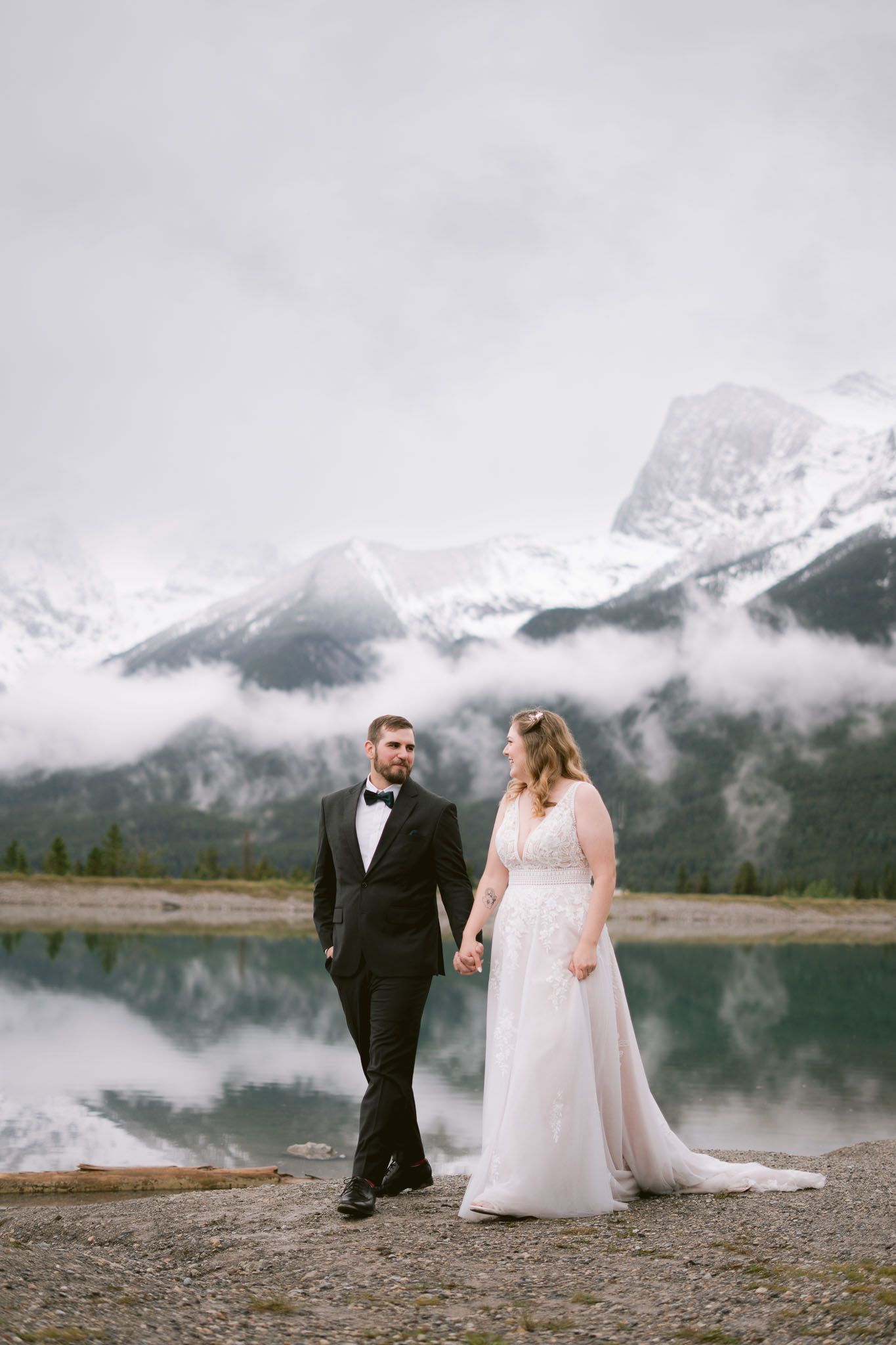 Wedding photos with dramatic mountain landscape and misty lake backdrop in Canmore. Alberta
