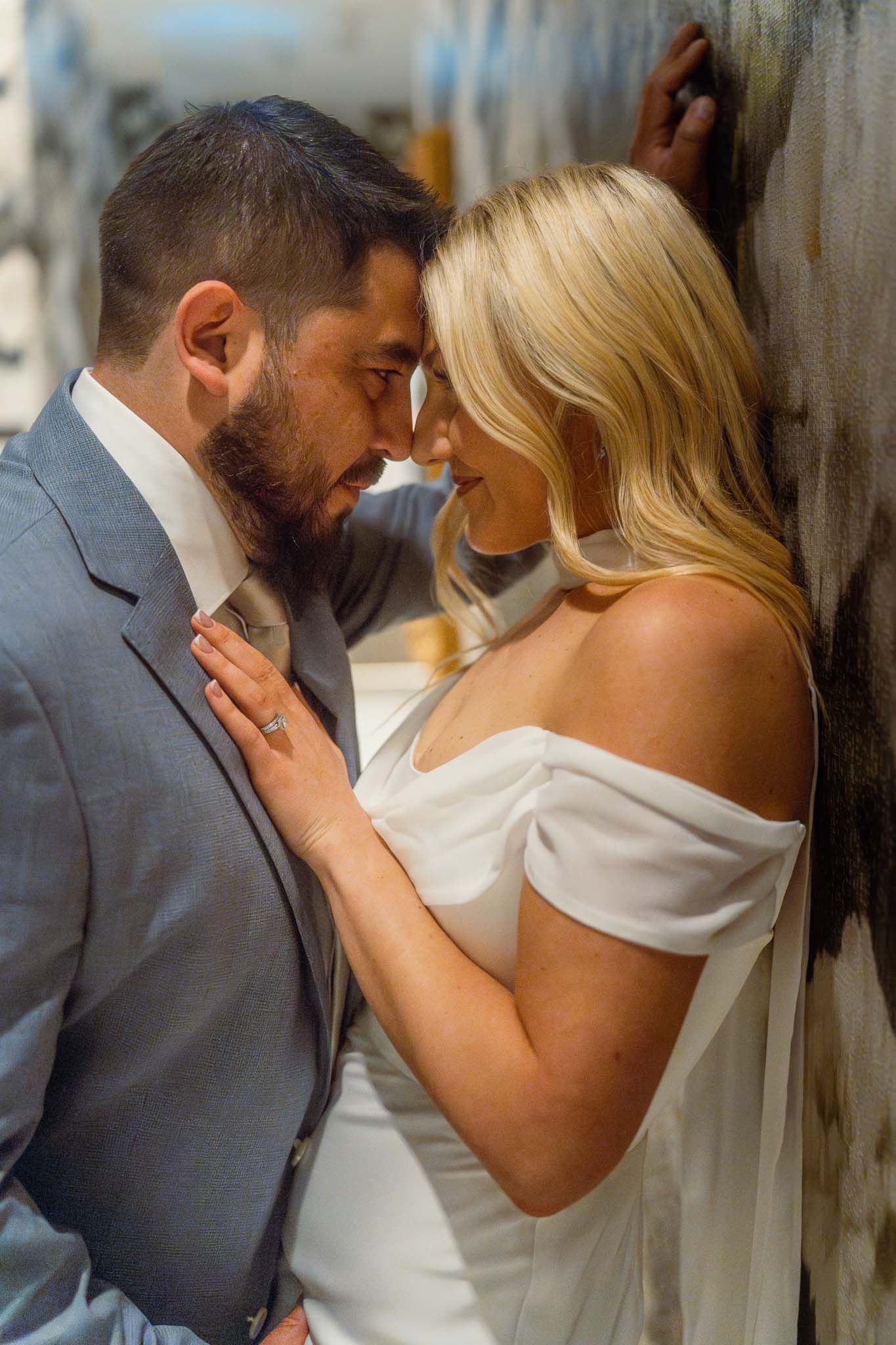 Romantic wedding portraits showing tender moments between newlyweds against a textured wall.