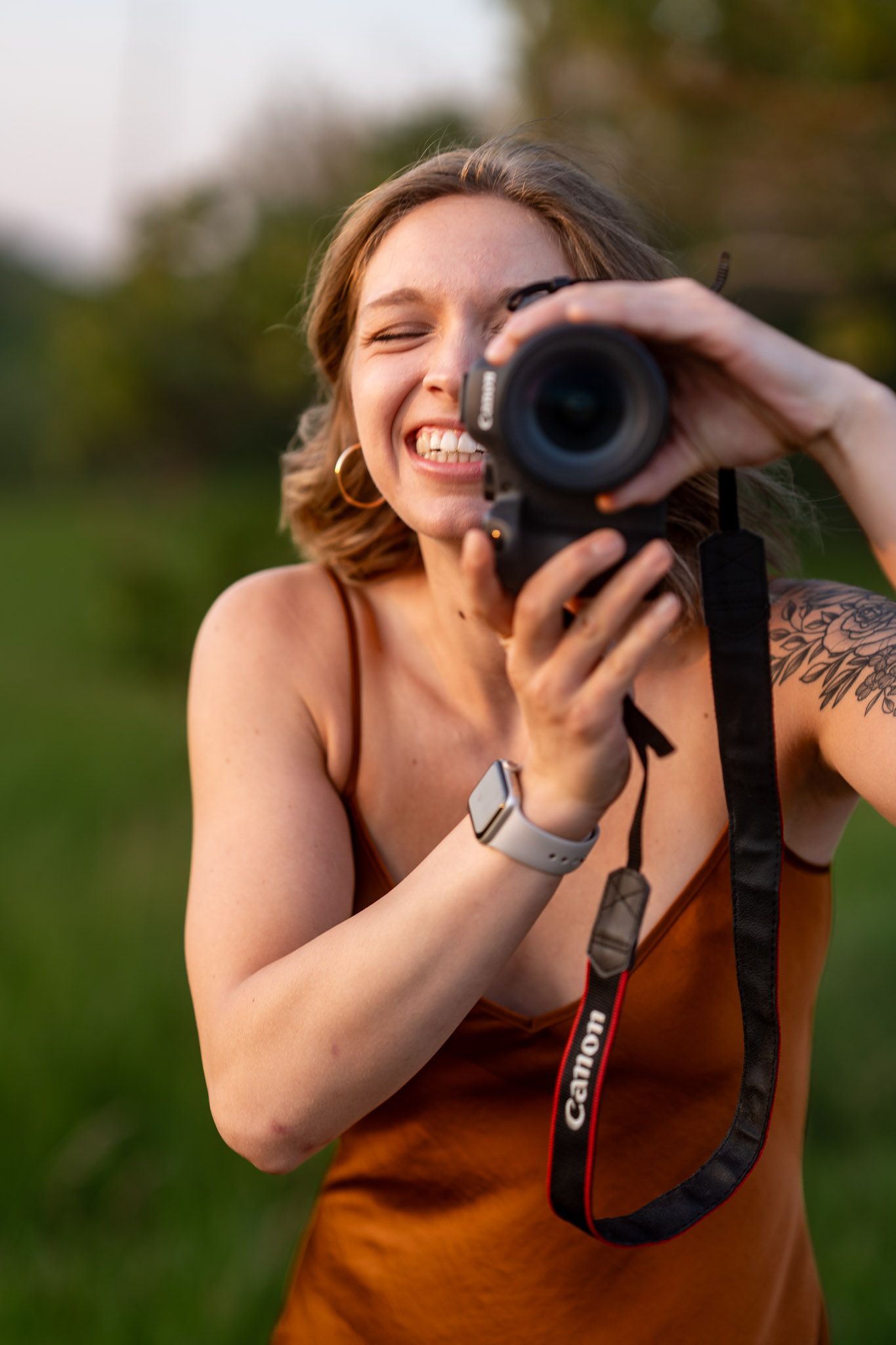 Photographer in orange tank top capturing photos during golden hour.