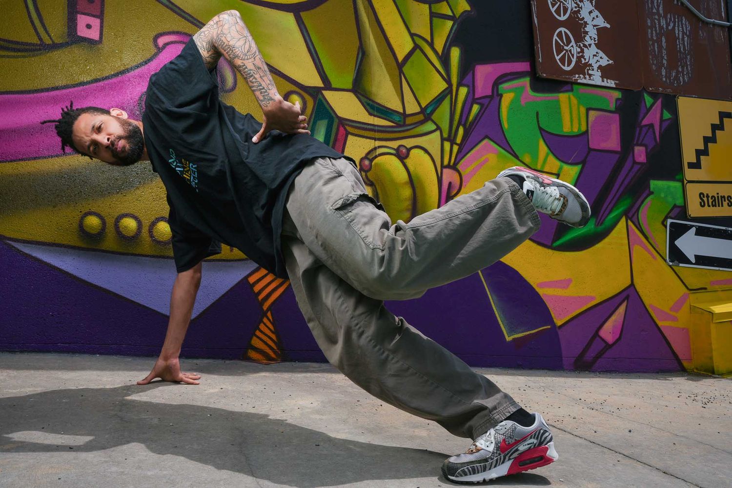 Dynamic breakdancing moves showcased against vibrant street art background.