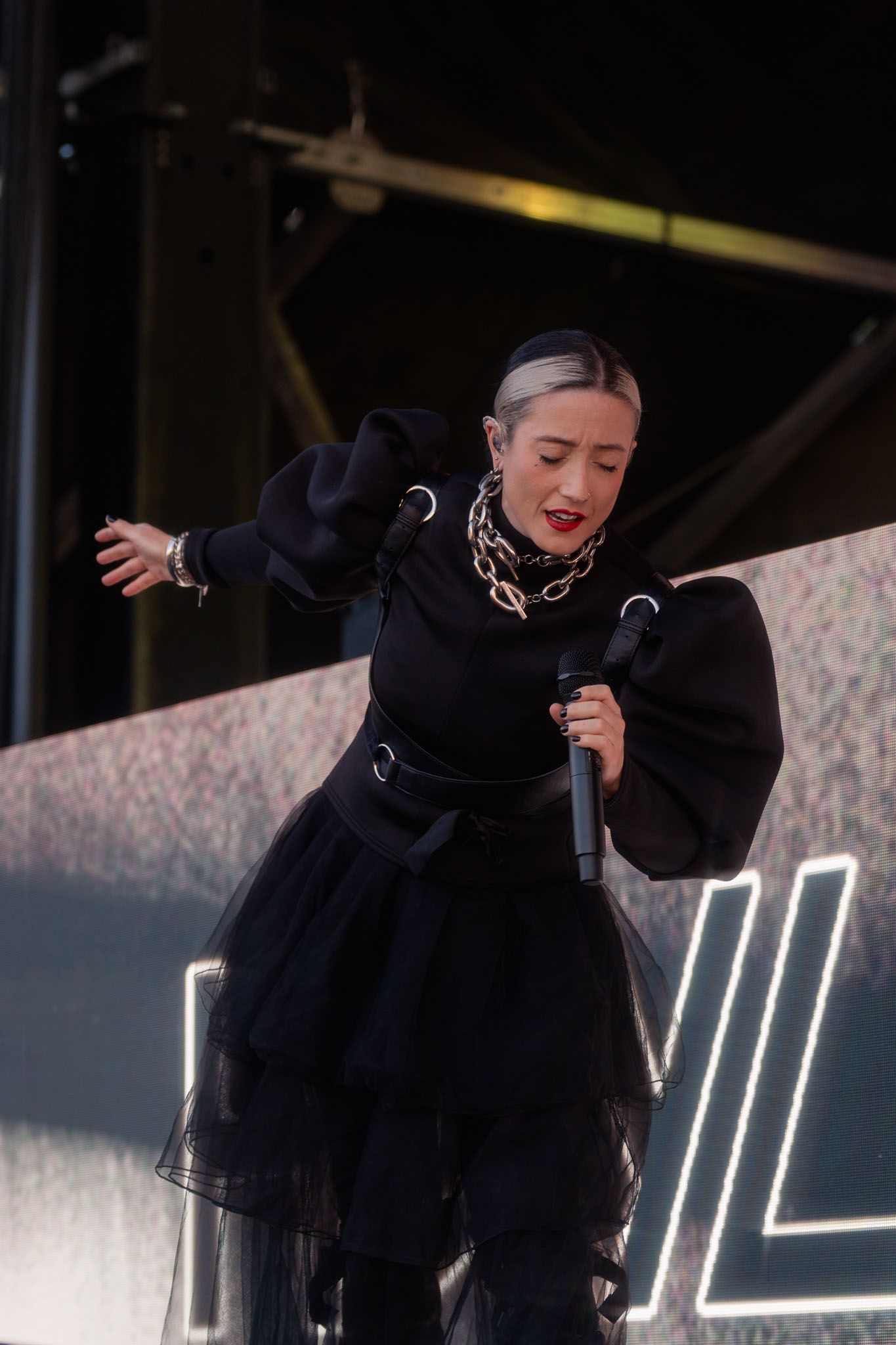 Stage performer Hayla in black outfit making expressive movements during live show.