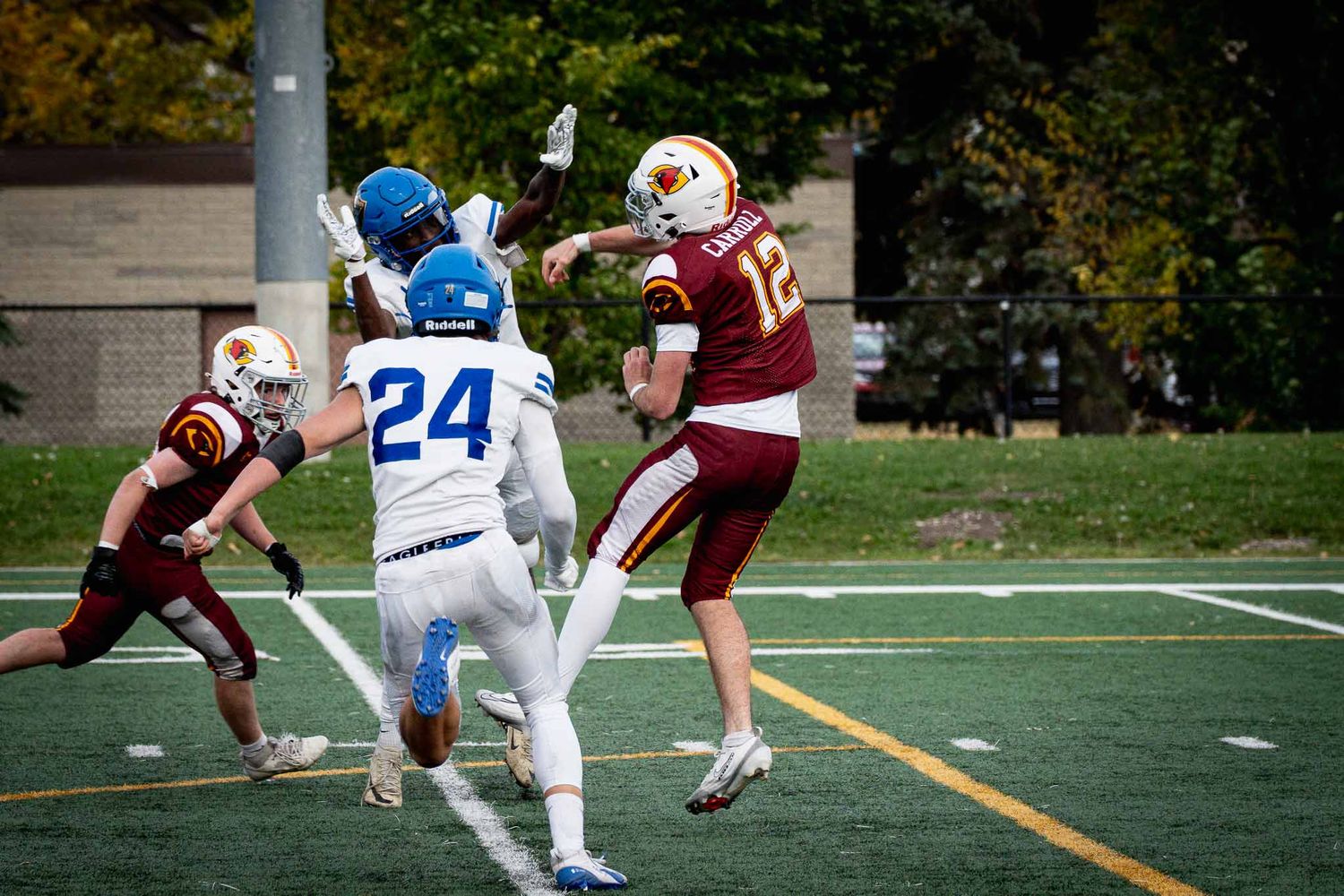 Football play showing defensive tackle between players in maroon and white jerseys.