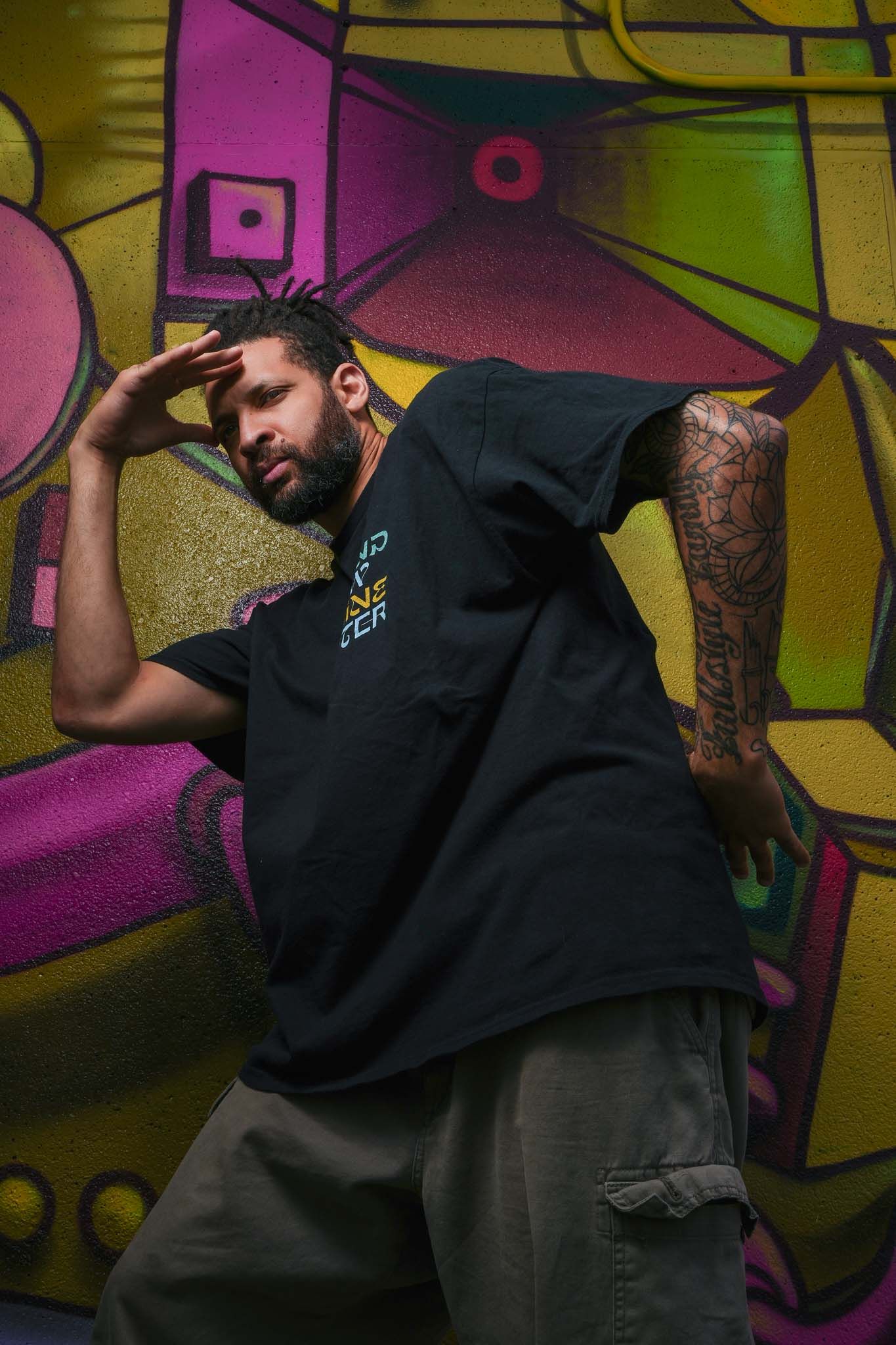 Urban dancer performs dynamic movements against colorful street art backdrop.