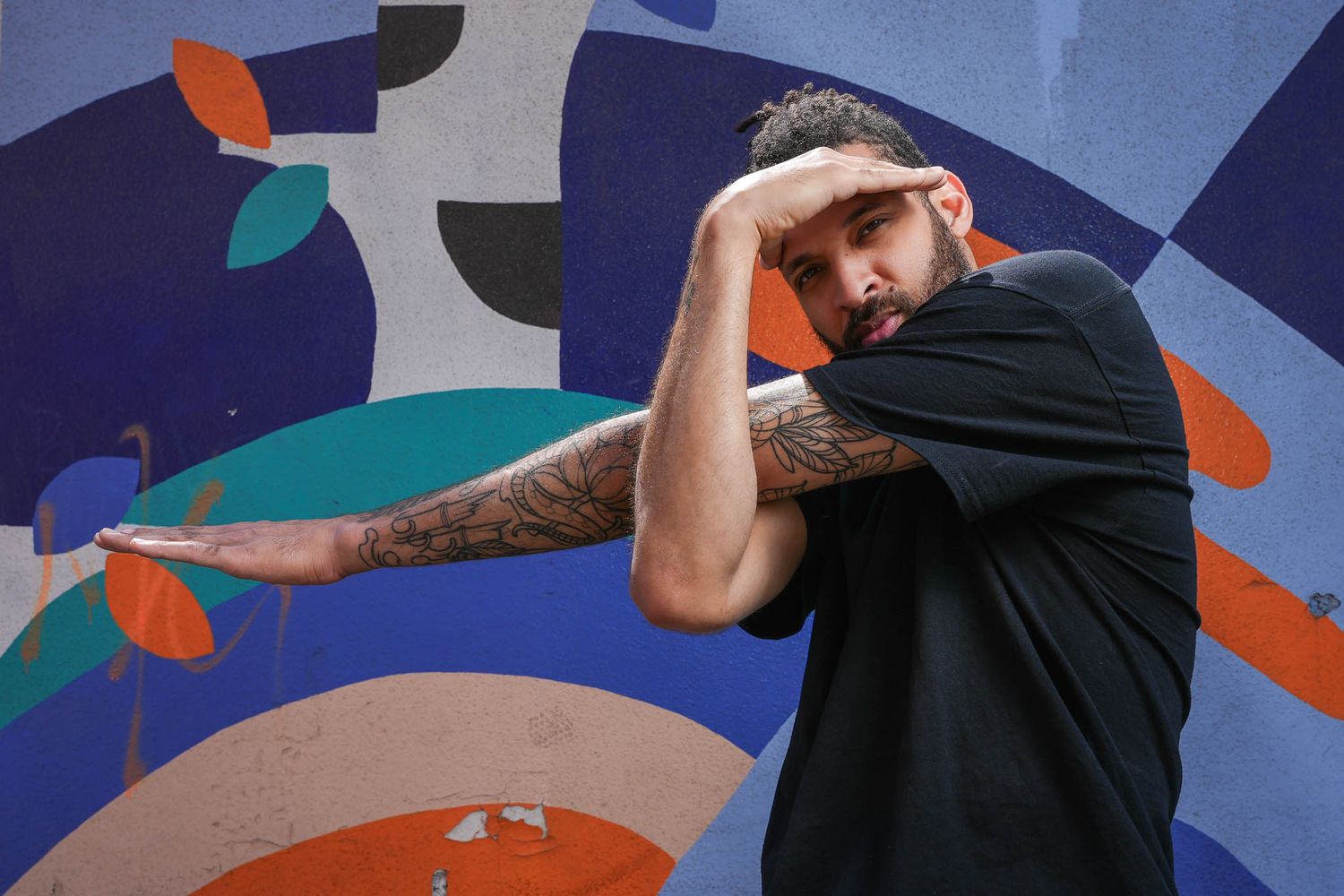 Artistic portraits against vibrant blue and orange geometric mural background.
