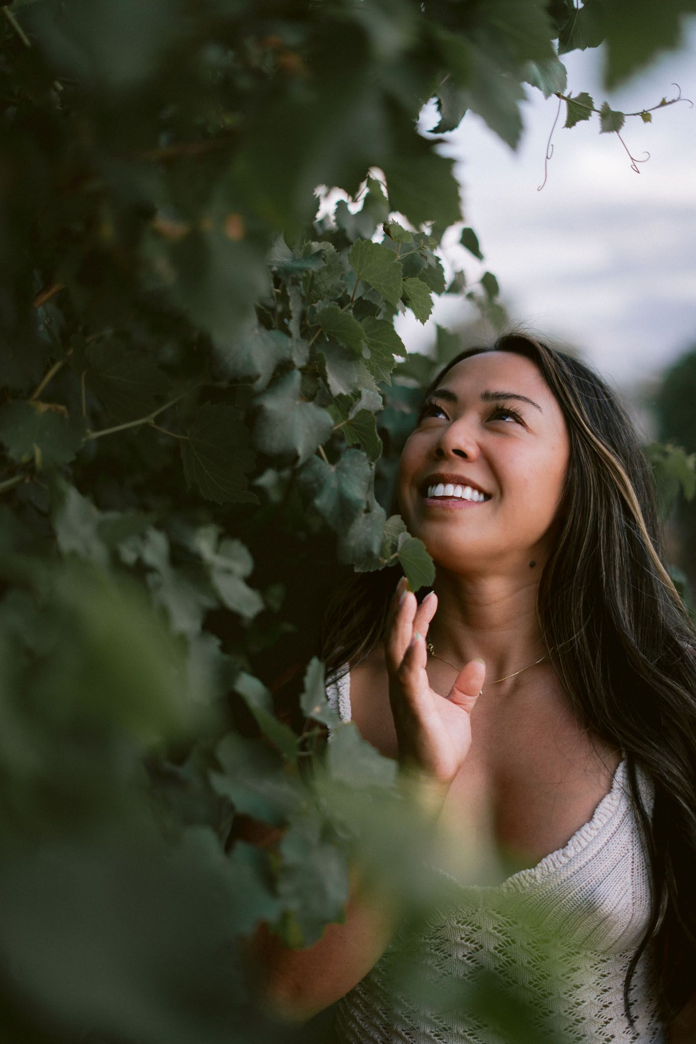 Joyful portrait through green foliage with natural lighting and soft focus in Italian vineyard