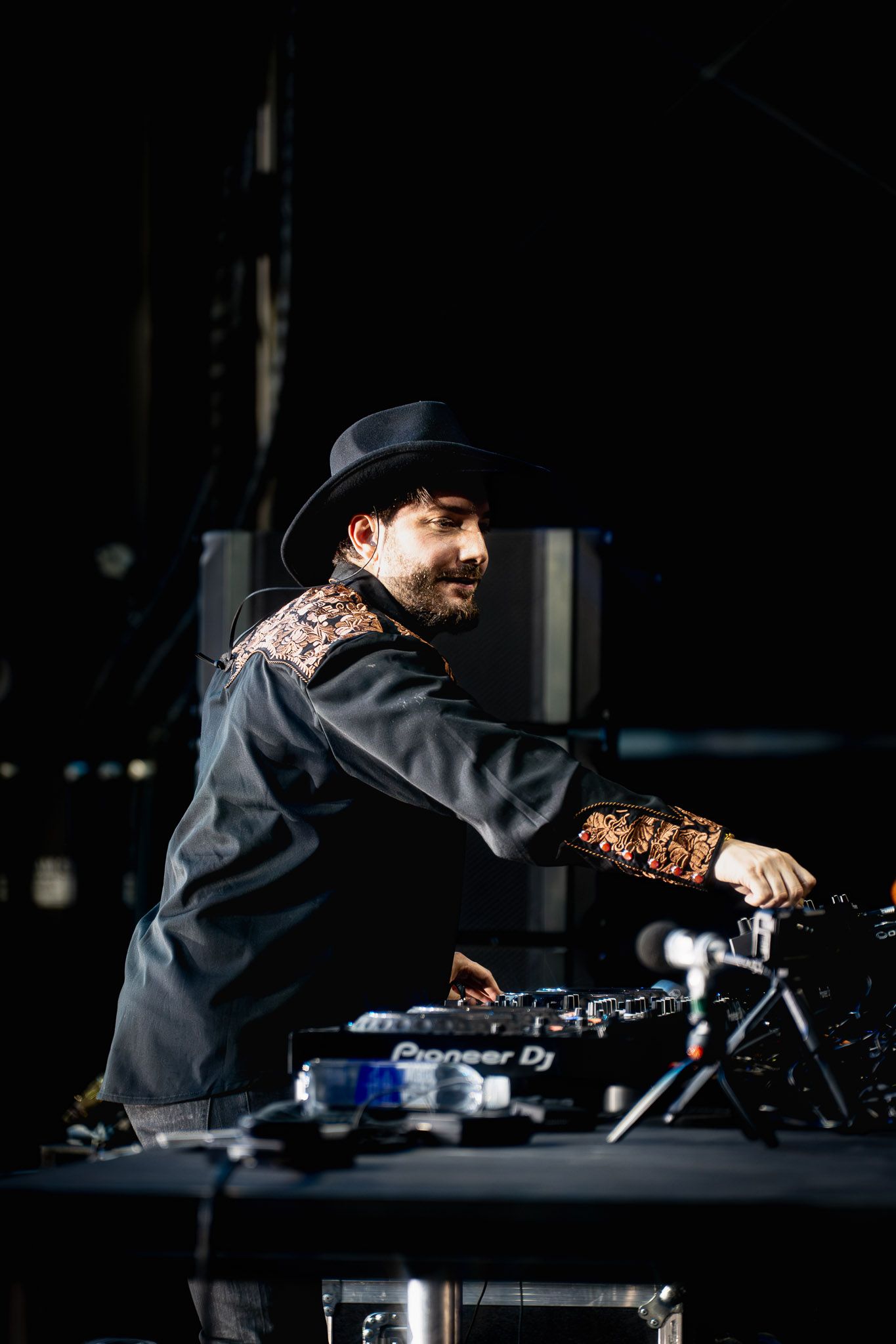 DJ Alesso in dark attire mixing music at professional turntables during performance.