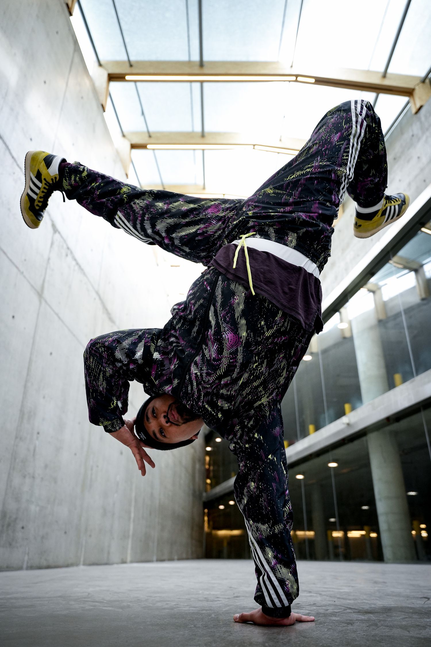 Breakdancer executes dynamic power moves in concrete indoor setting.