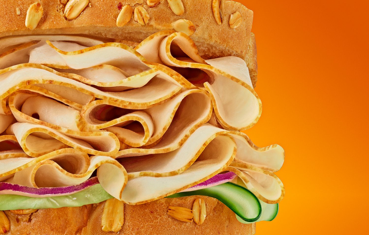 Close-up of sandwich layers with peanuts and vegetables against orange background.