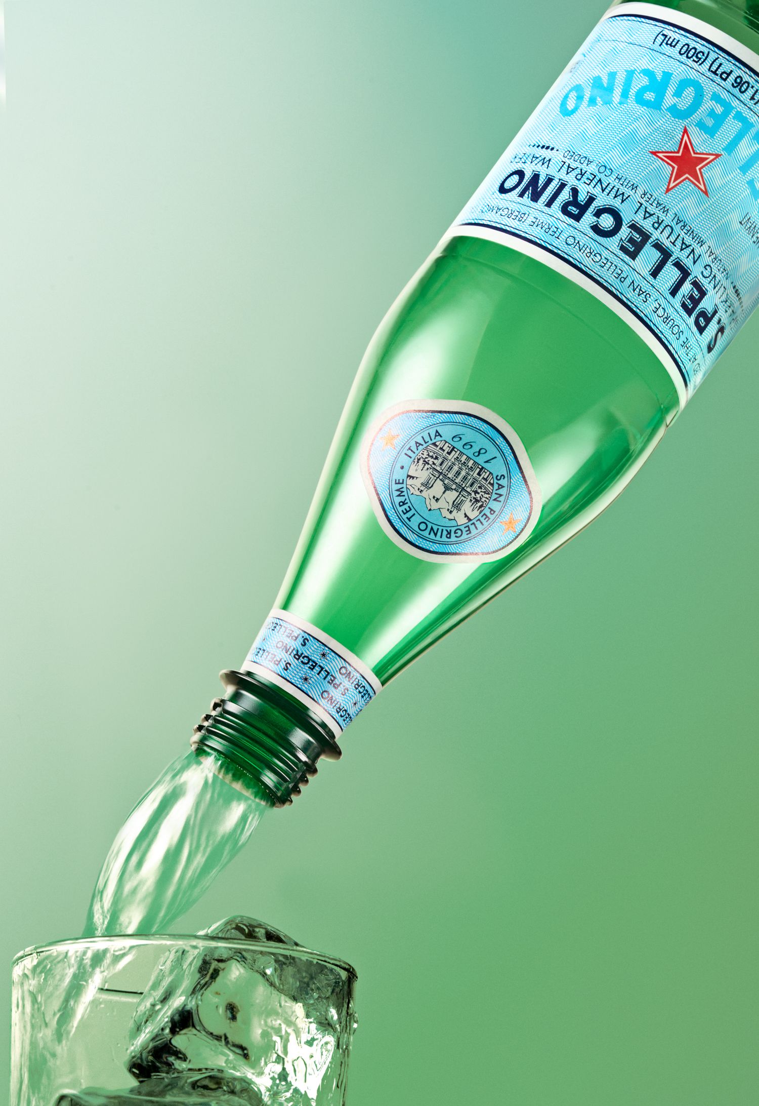 San Pellegrino bottle pouring sparkling water into glass with green gradient background.