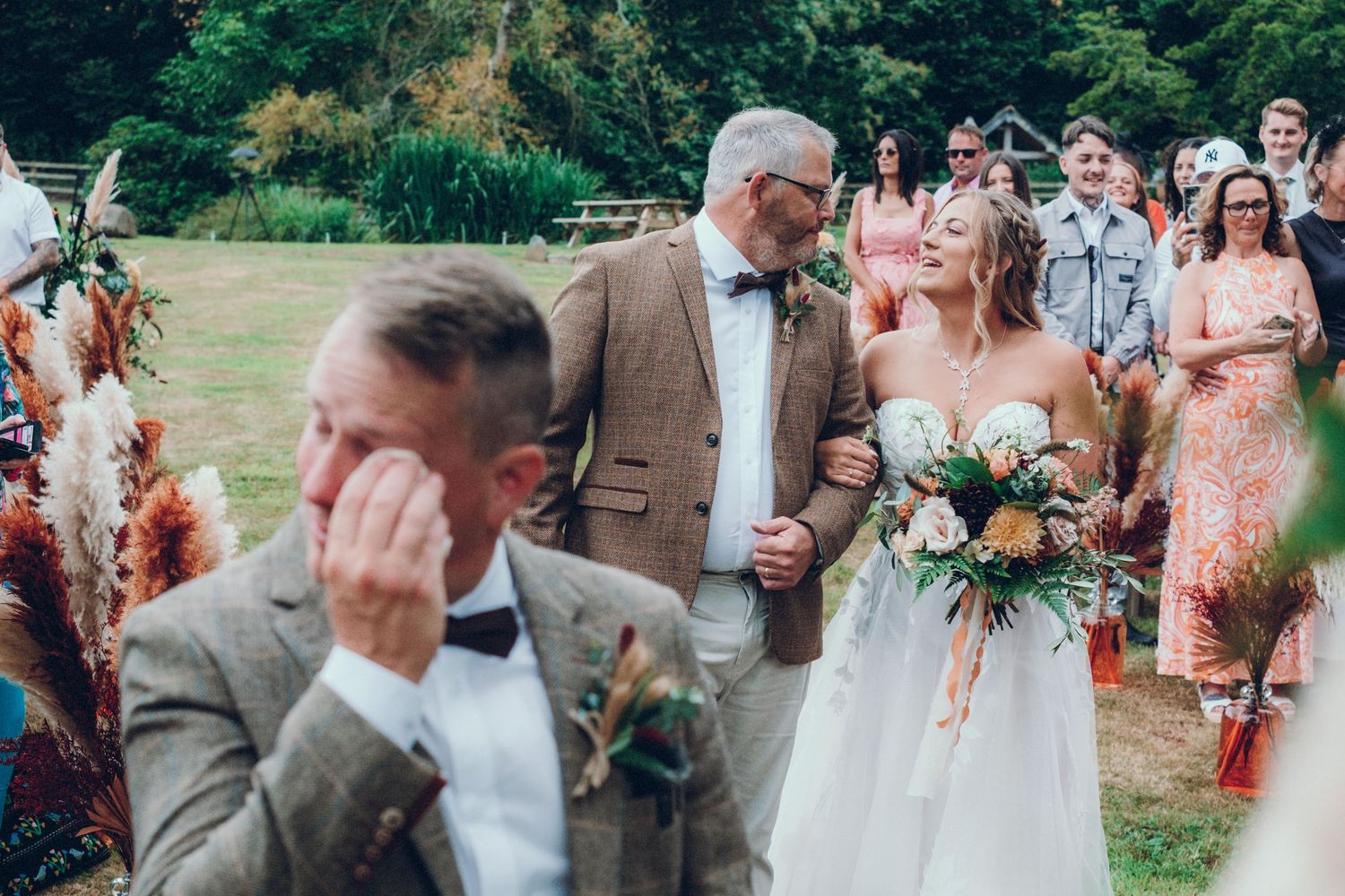 An emotional wedding ceremony moment outdoors with guests watching in a garden setting.