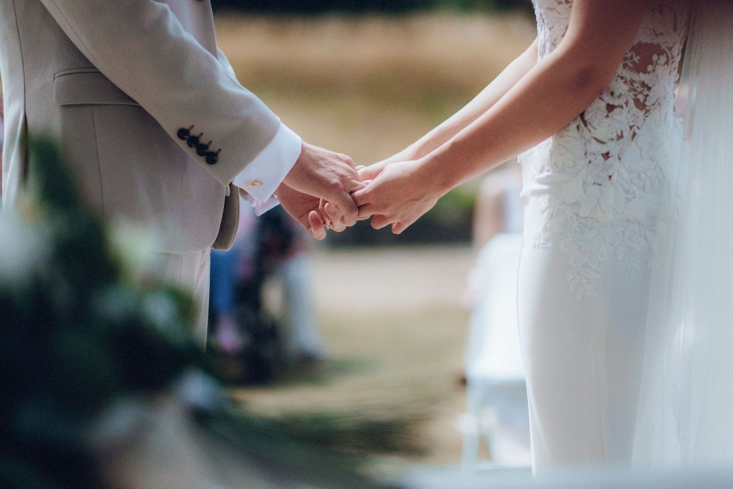 Close-up of couple exchanging rings during outdoor wedding ceremony.