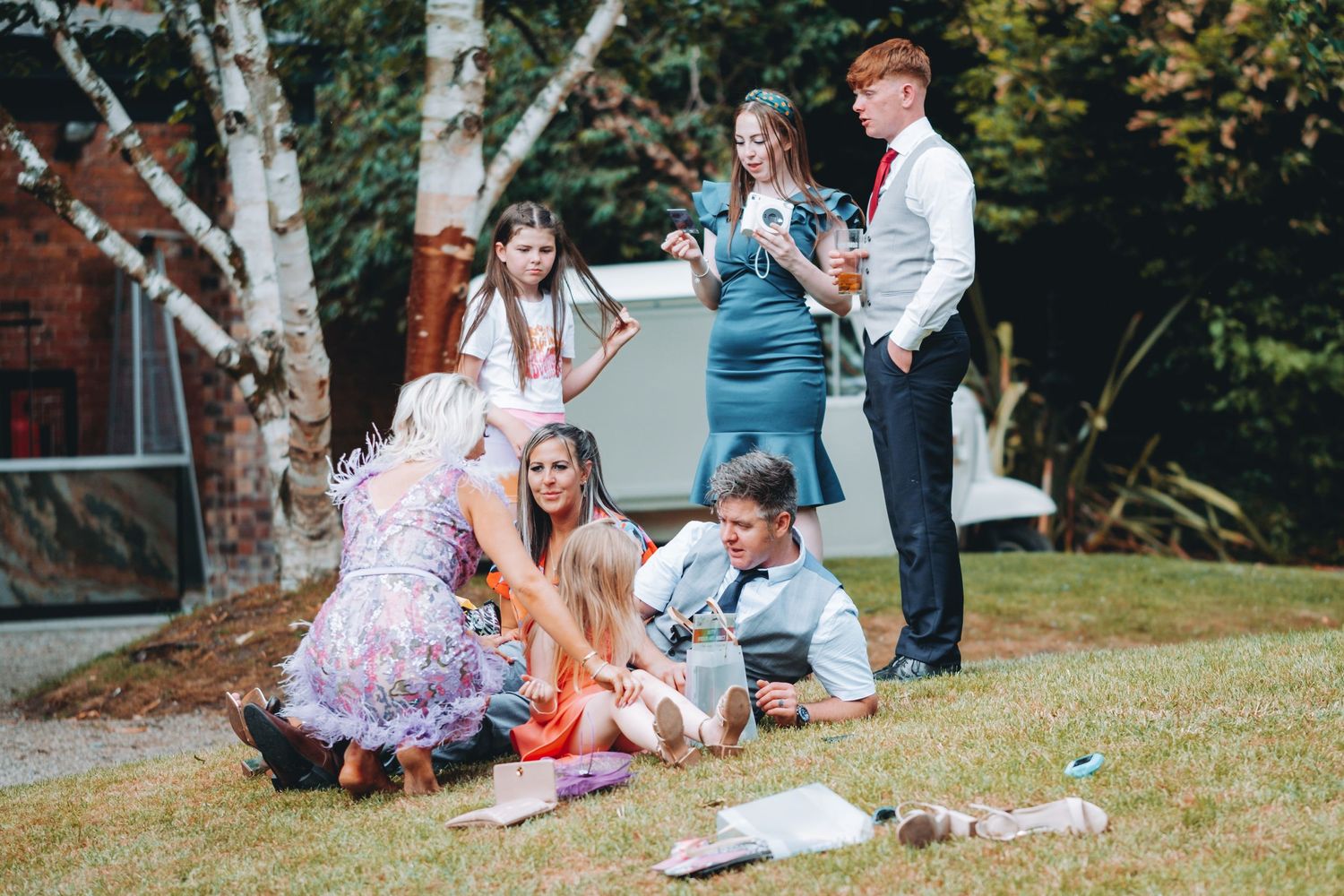 Wedding guests relaxing on grassy lawn during outdoor celebration.
