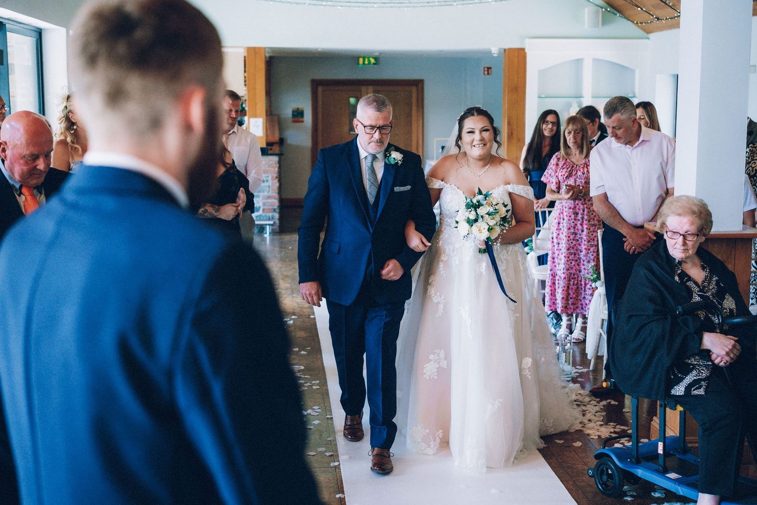Wedding guests gathering in a bright modern venue with blue accents.