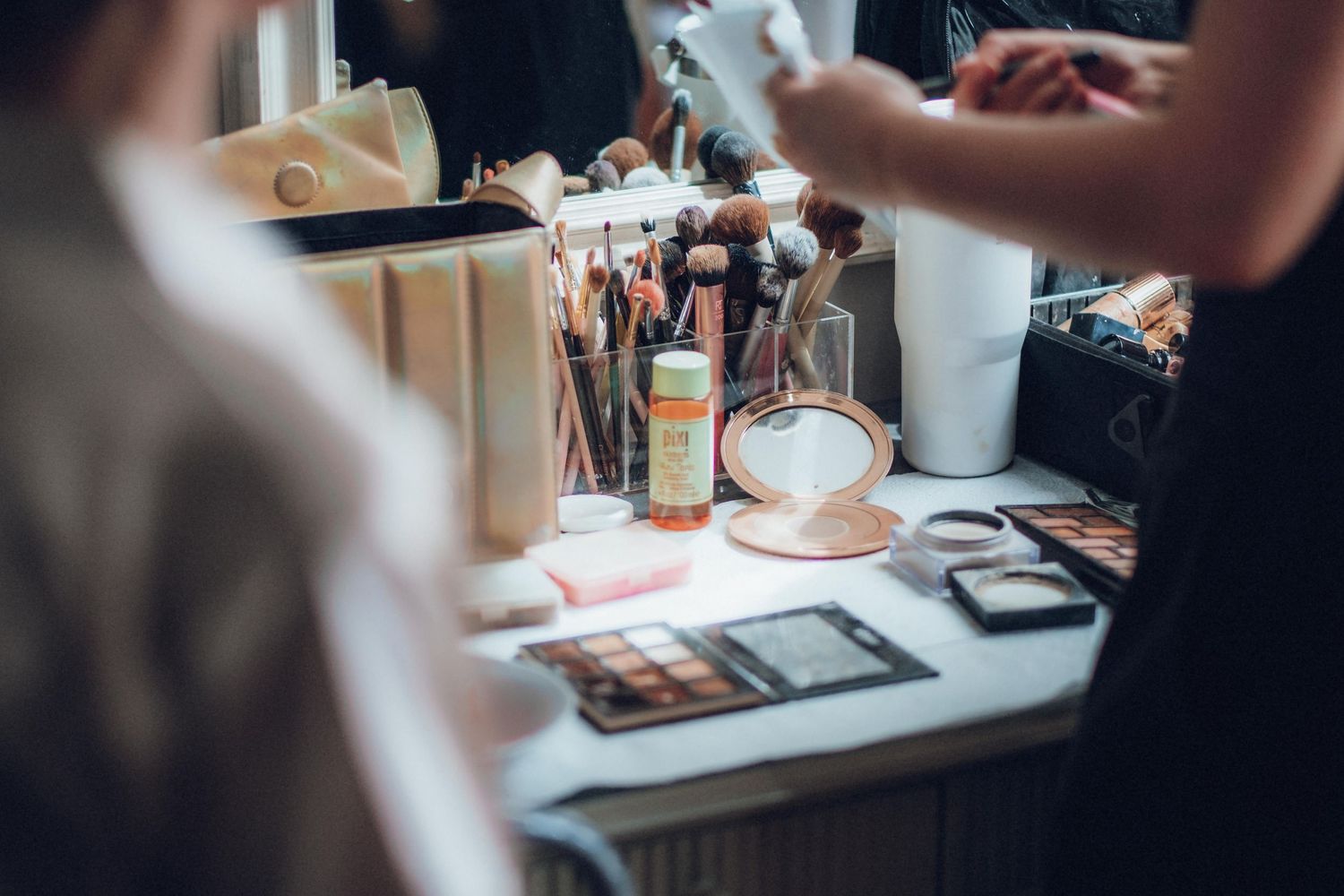 Close-up of wedding day preparations with makeup supplies and styling tools on table.