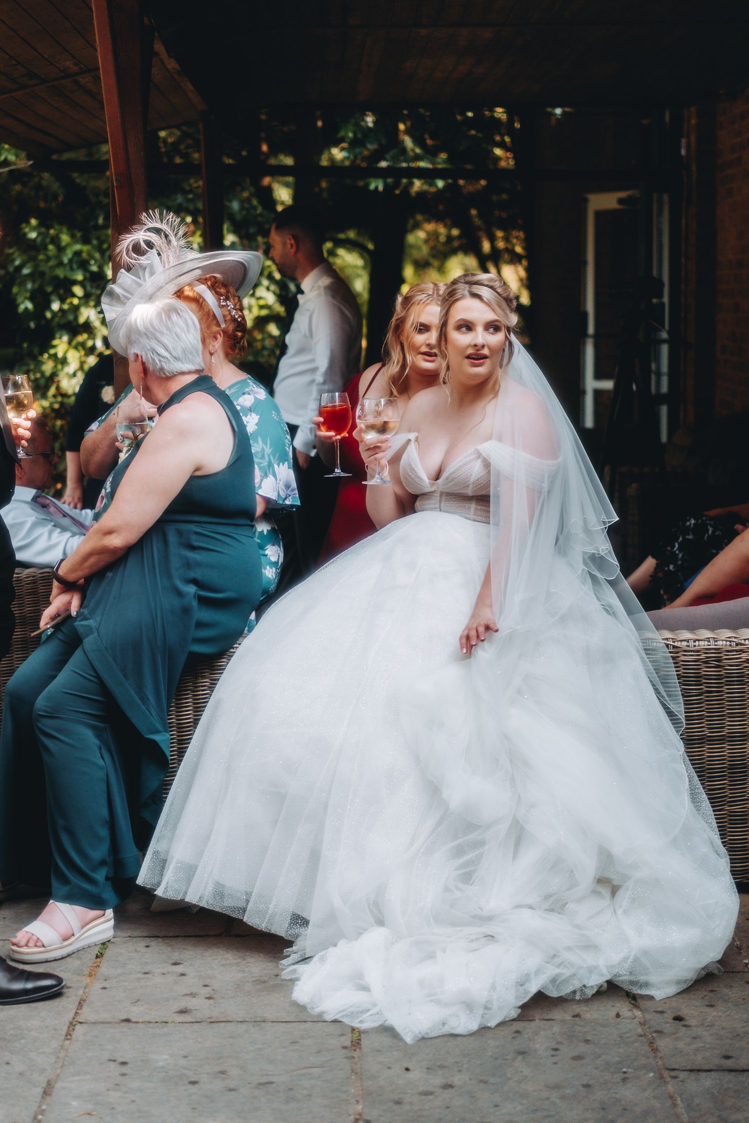 People enjoying a wedding at an outdoor venue with bride in a flowing white bridal gown and floral veil.