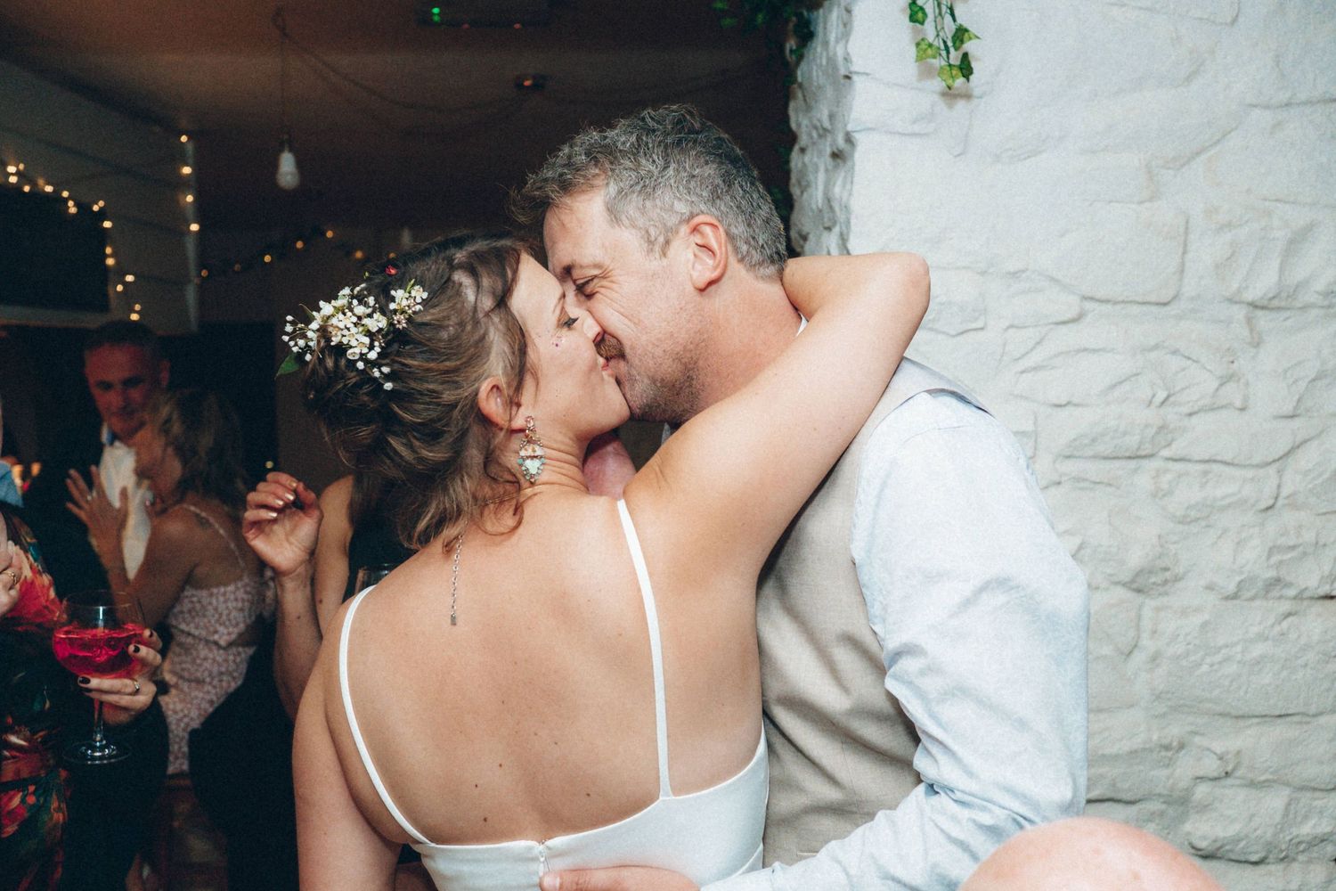 Couples dancing together during romantic wedding reception in rustic venue with white stone walls.