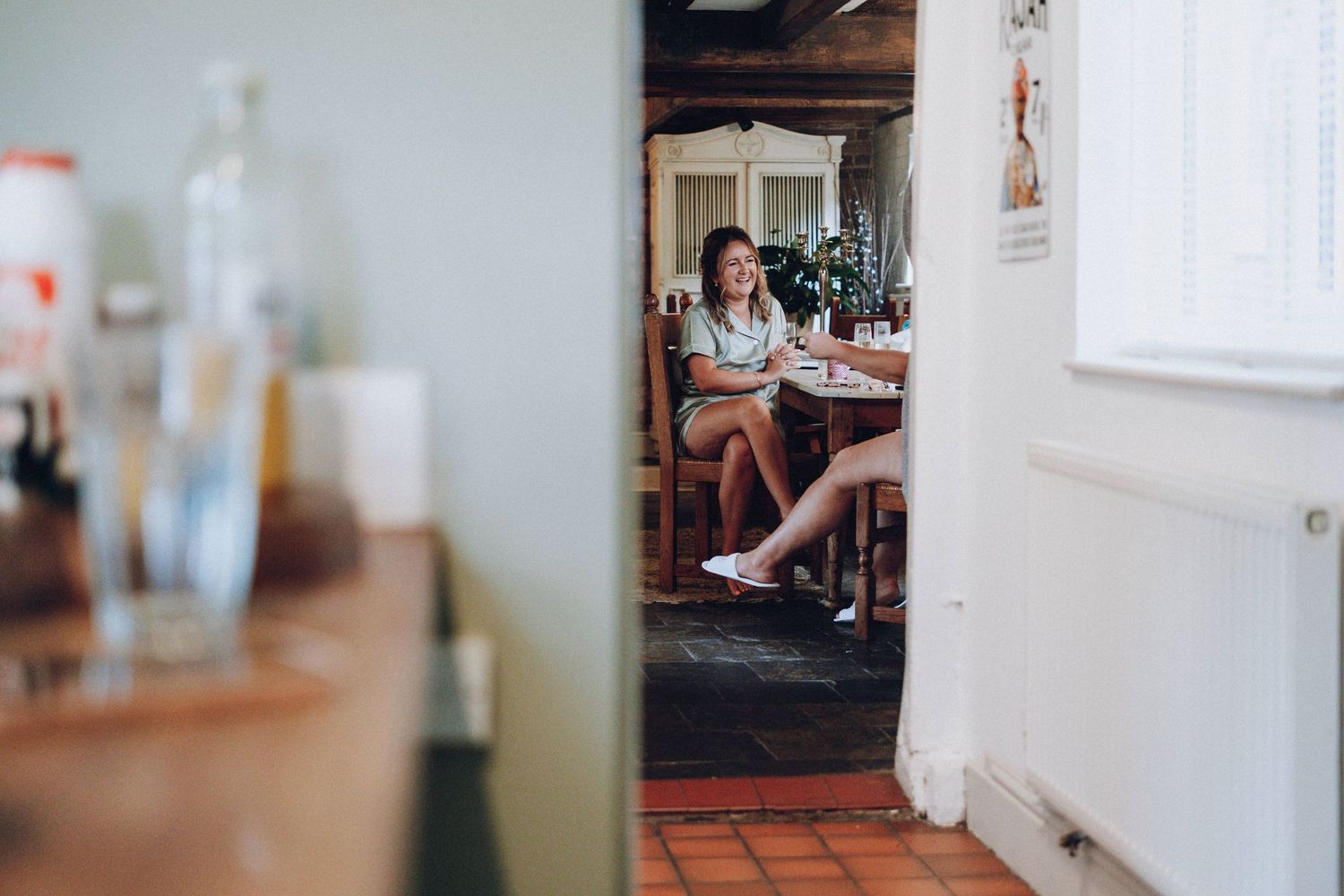 View through doorway of someone sitting in a rustic kitchen interior.