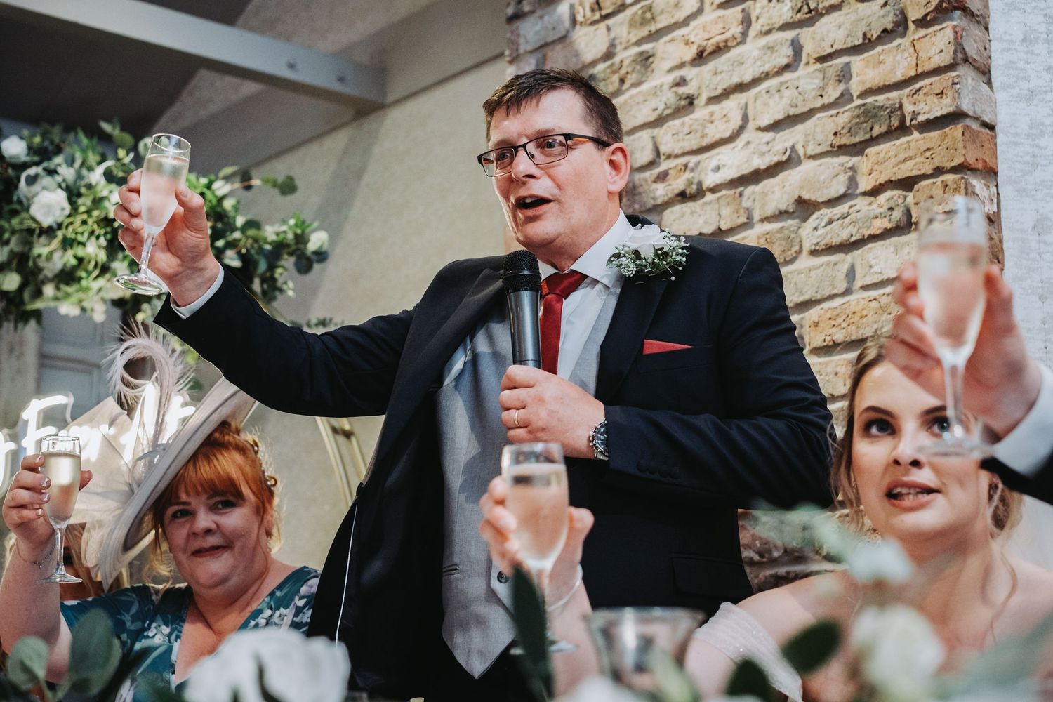 Wedding reception toast moment with champagne glasses raised in celebration.
