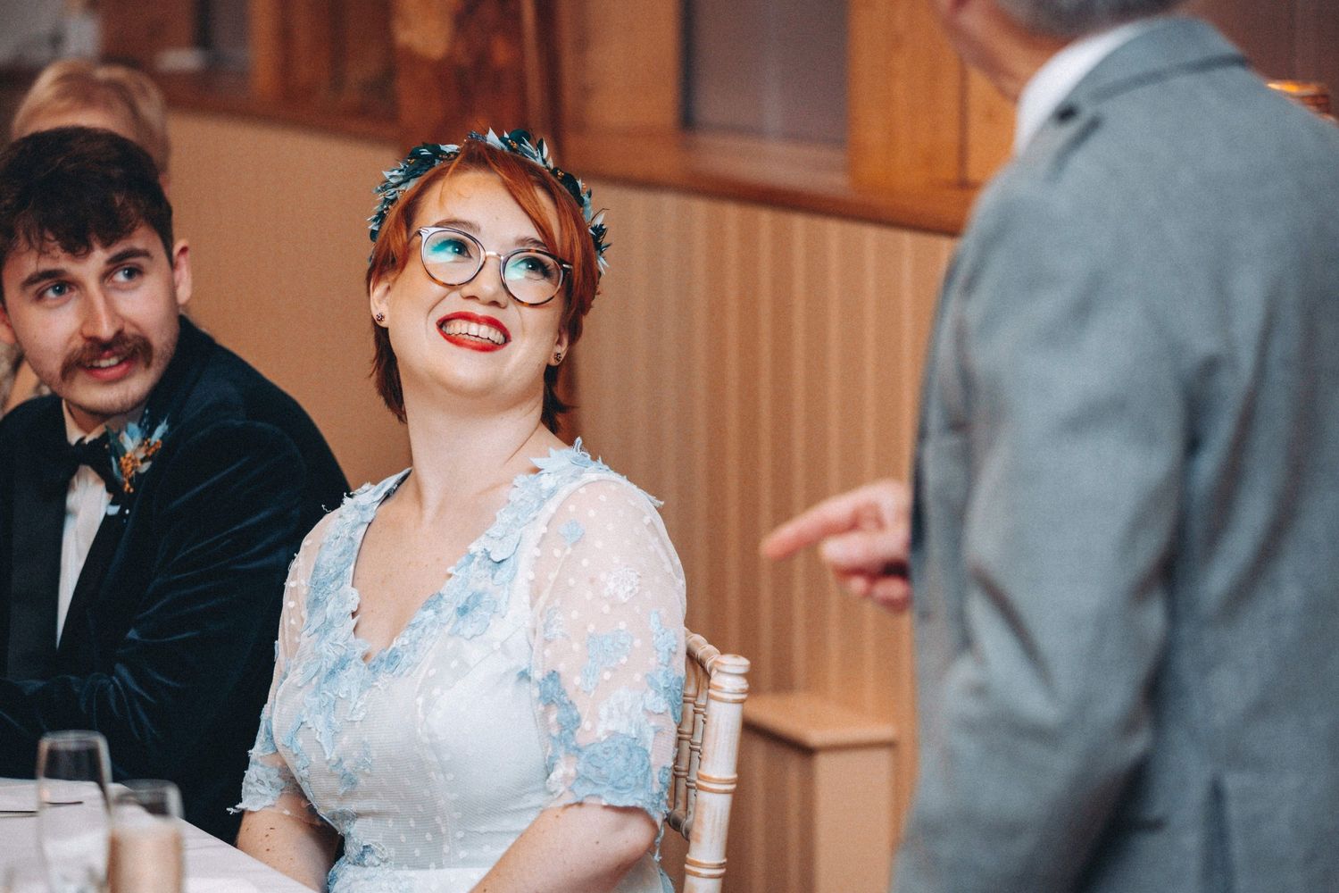 Candid moment during wedding reception with guests laughing at dinner tables.