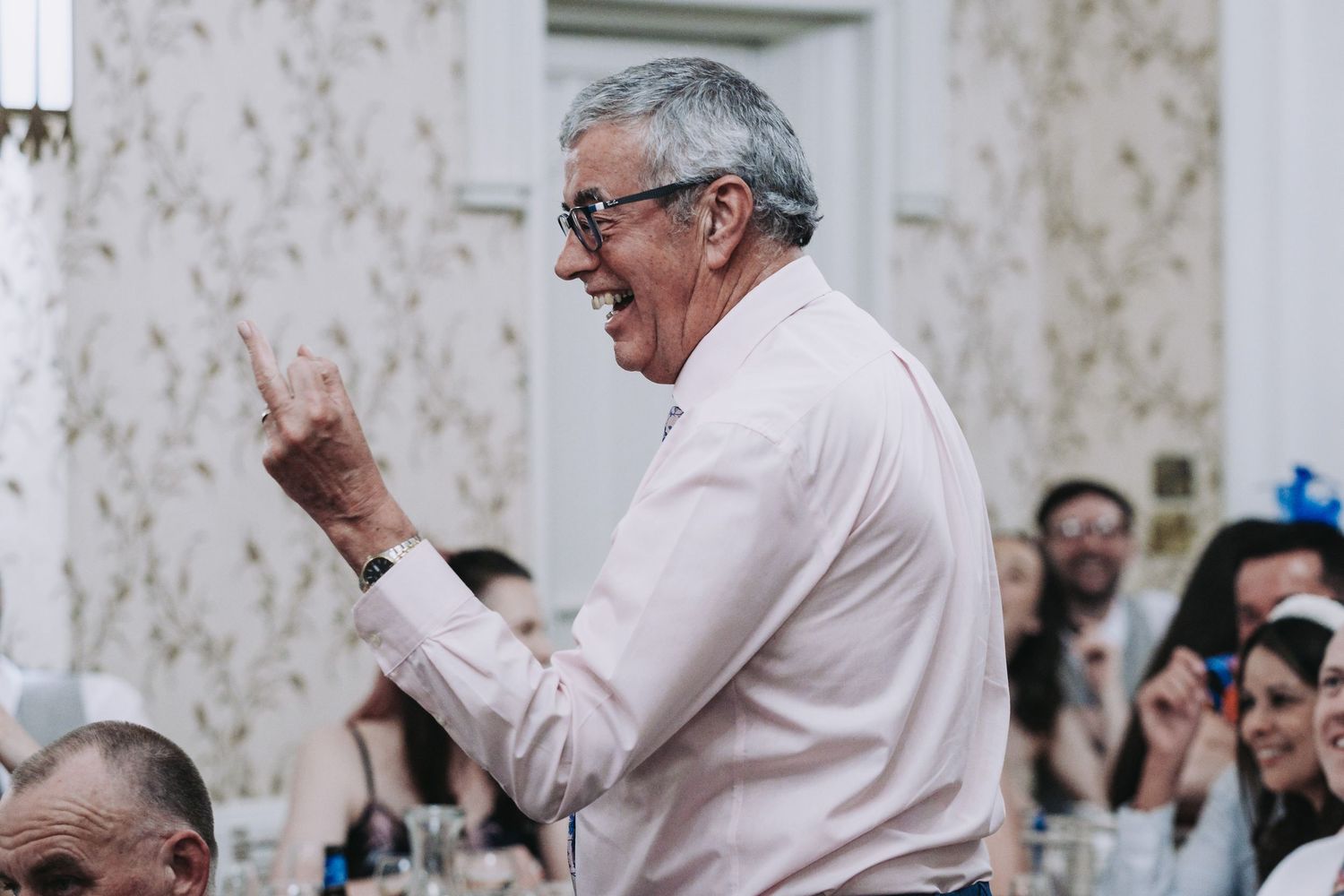 Wedding guests react with joy and laughter during reception speeches.