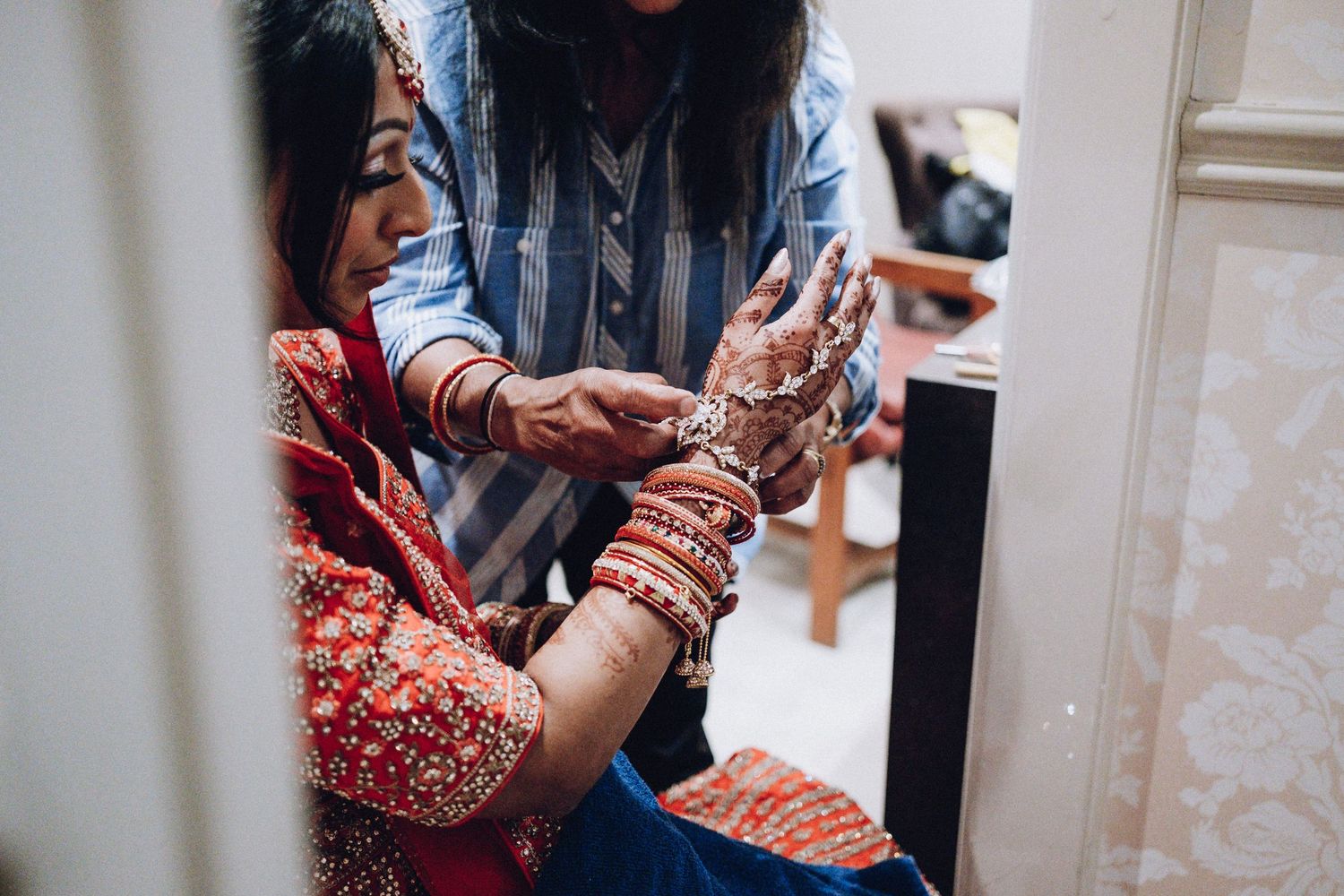 Close-up of intricate henna designs being applied to hands for wedding ceremony.