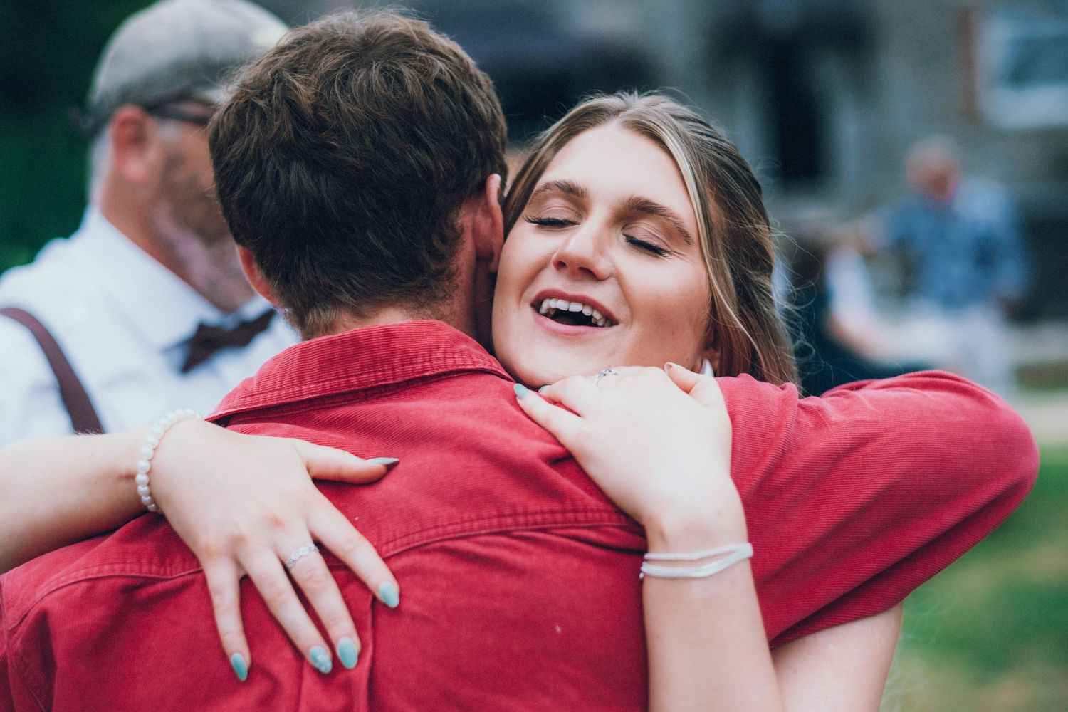 People share warm embraces wearing red and white attire at a celebration.