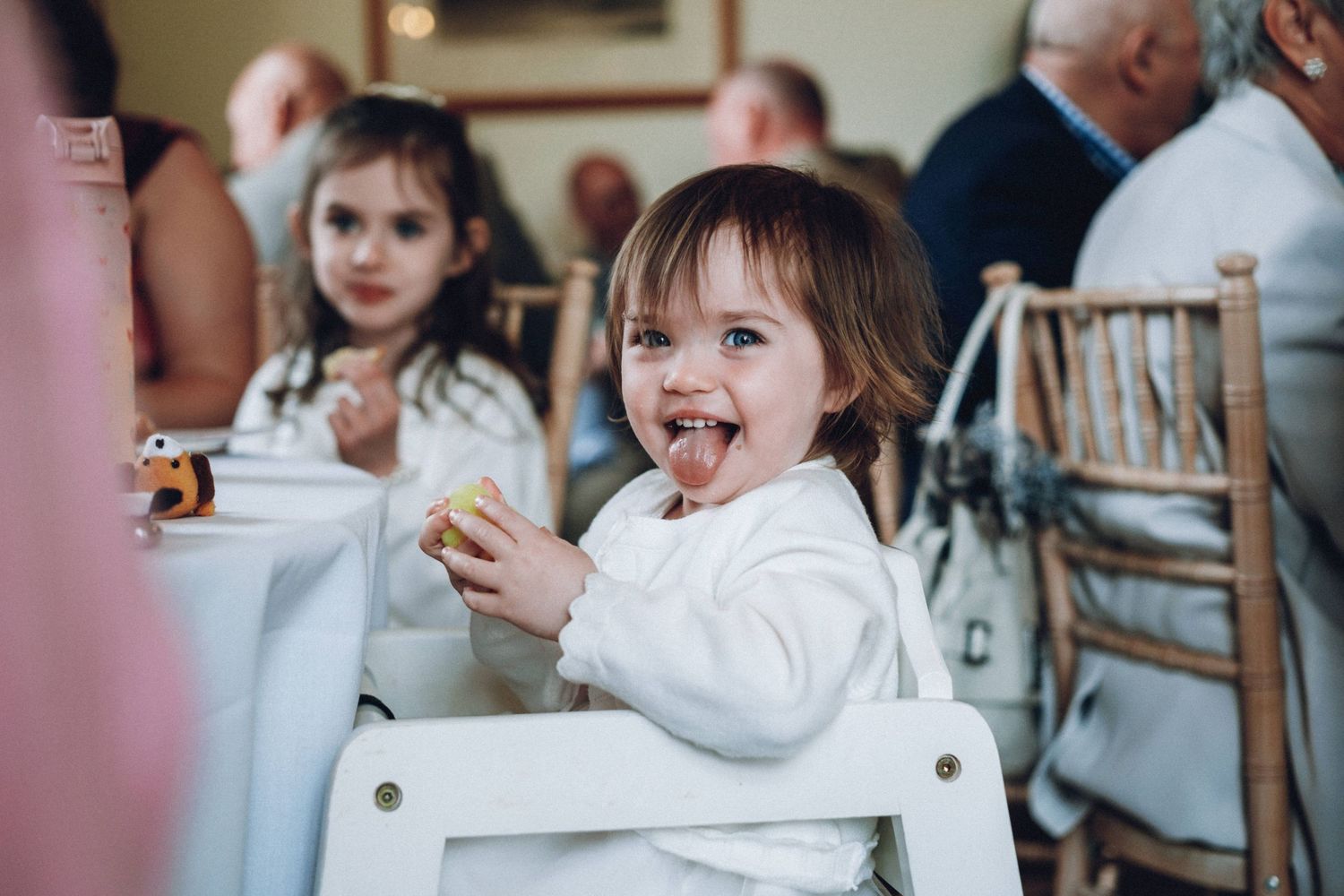 Children laugh and play during an indoor wedding reception.