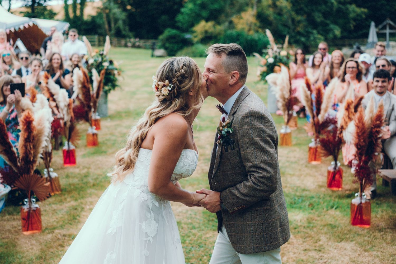 Joyful outdoor wedding celebration with guests throwing confetti and red cups in a garden setting.