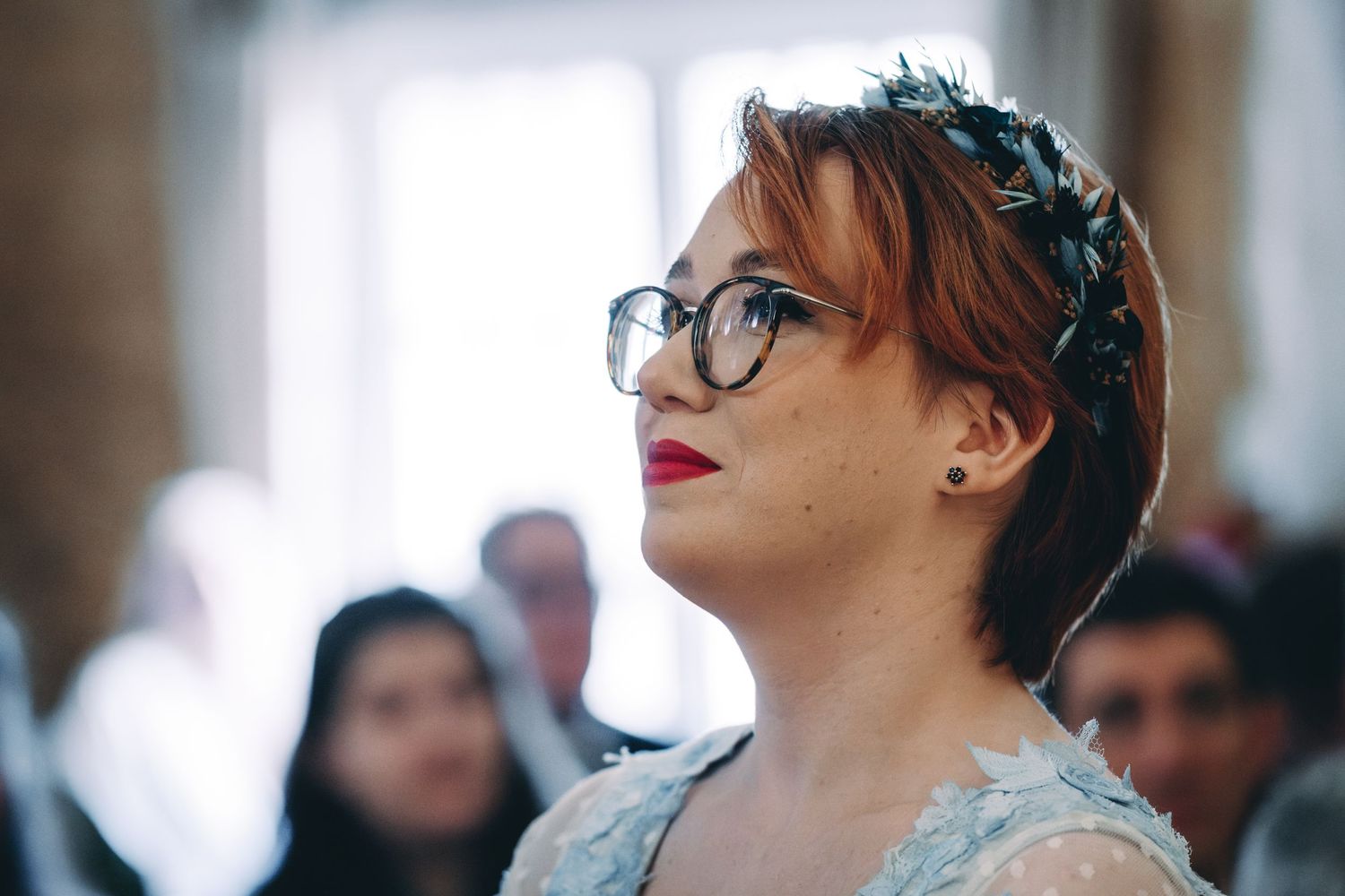 A guest in glasses and formal attire gazes upward during wedding celebration.