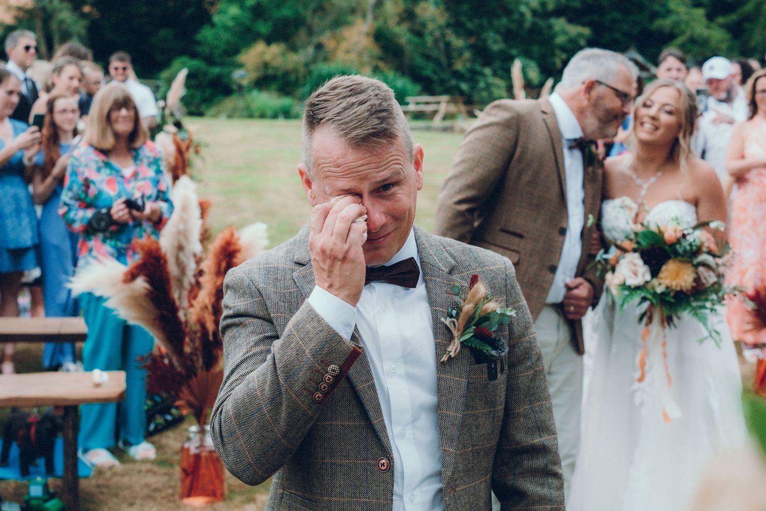 Wedding guests celebrate outdoors at a summer garden reception with joyful expressions and natural scenery.