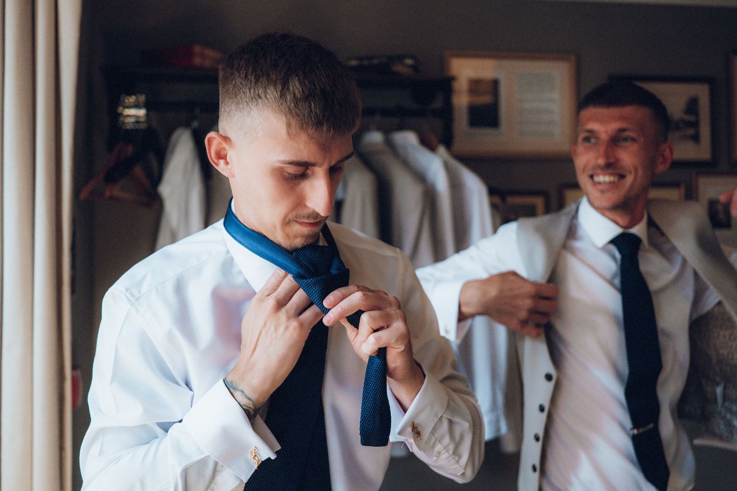 Wedding party members in formal attire share heartfelt embraces during pre-ceremony preparations.