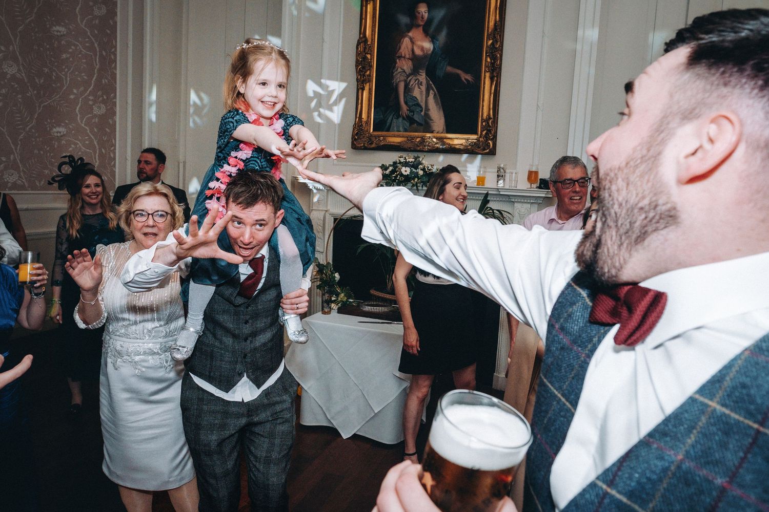 Guests enjoying themselves at a lively wedding reception with hands raised in celebration.