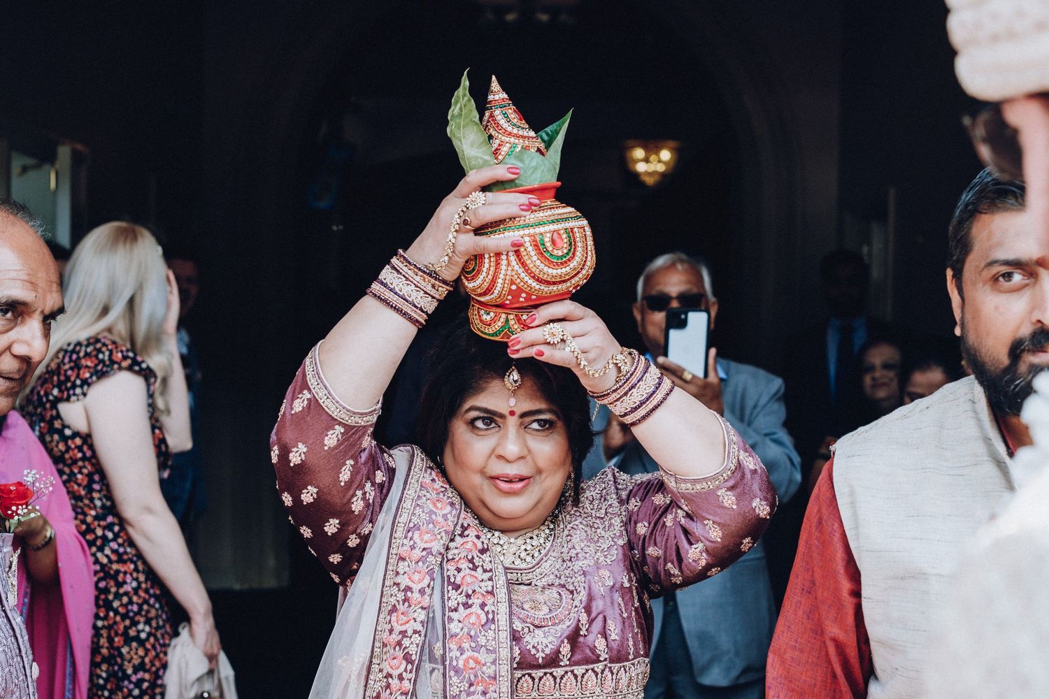 Wedding guest in traditional Indian attire holds decorative crown during celebration.