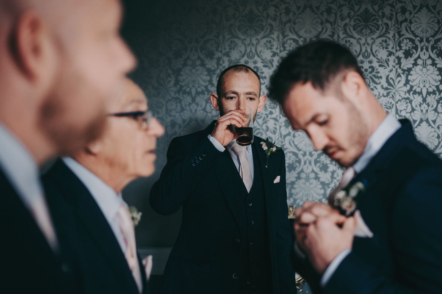 Groomsmen in formal black suits and bowties share a quiet moment before the wedding ceremony.
