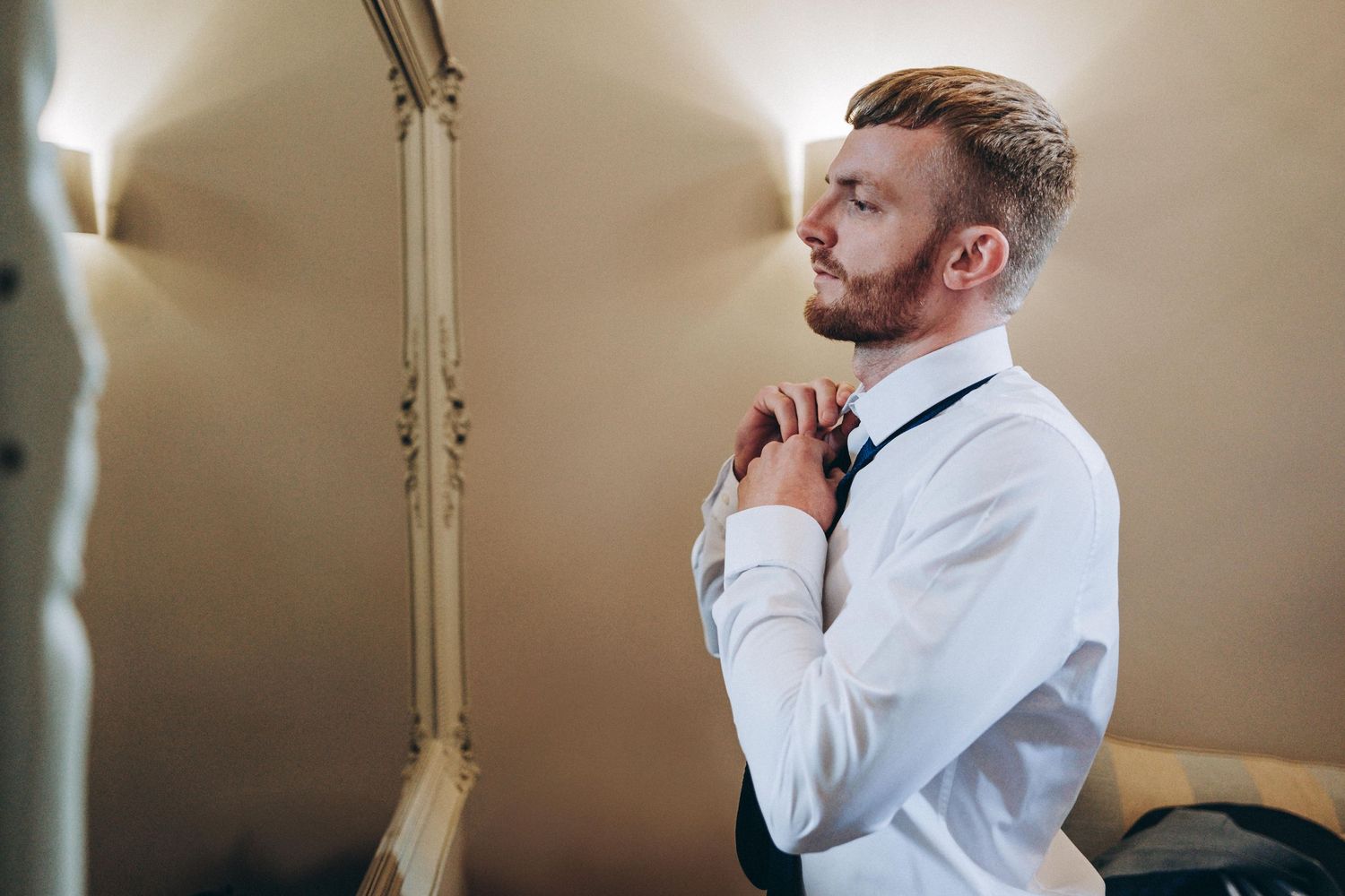 Someone adjusts their tie while getting dressed in formal attire.