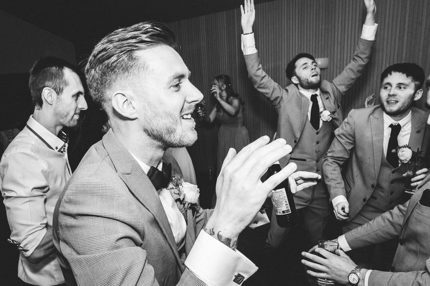 Wedding guests dancing and celebrating energetically at an indoor reception.