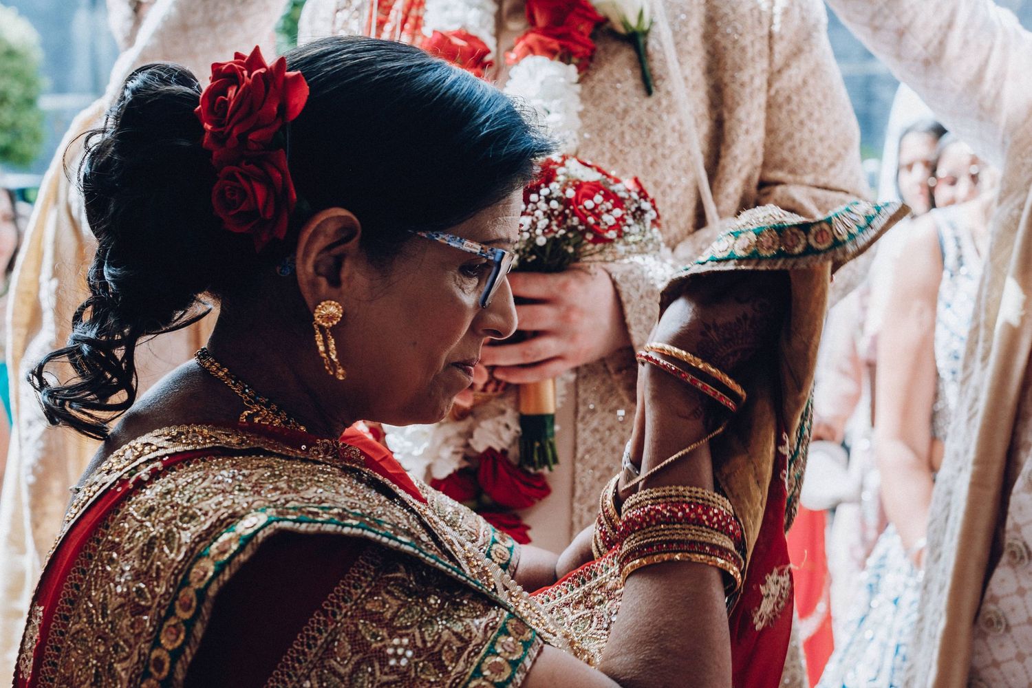 Traditional Indian wedding ritual with ornate jewelry and red floral decorations.