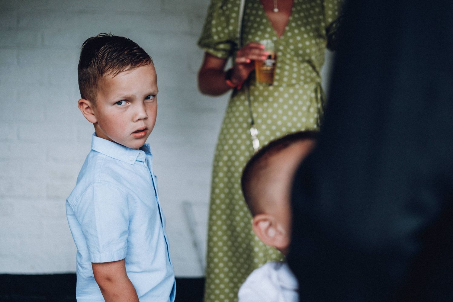 Young boy in light blue shirt looking to the side against dark background.