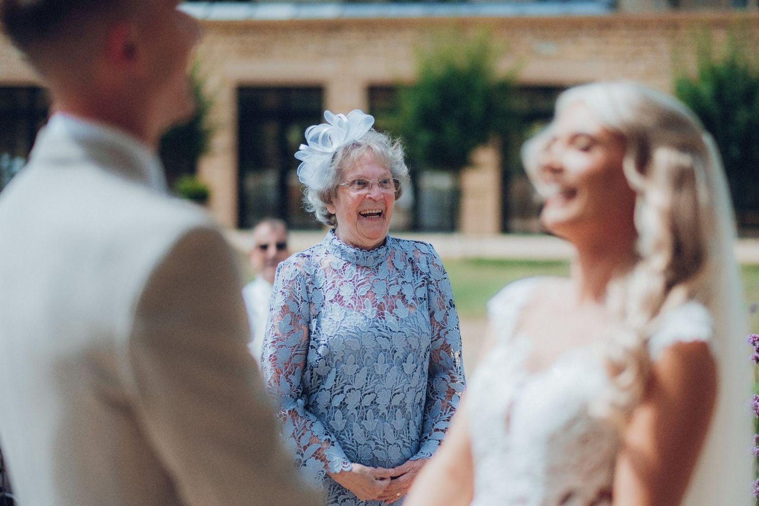 Wedding ceremony guests watching couple exchange vows in garden setting.