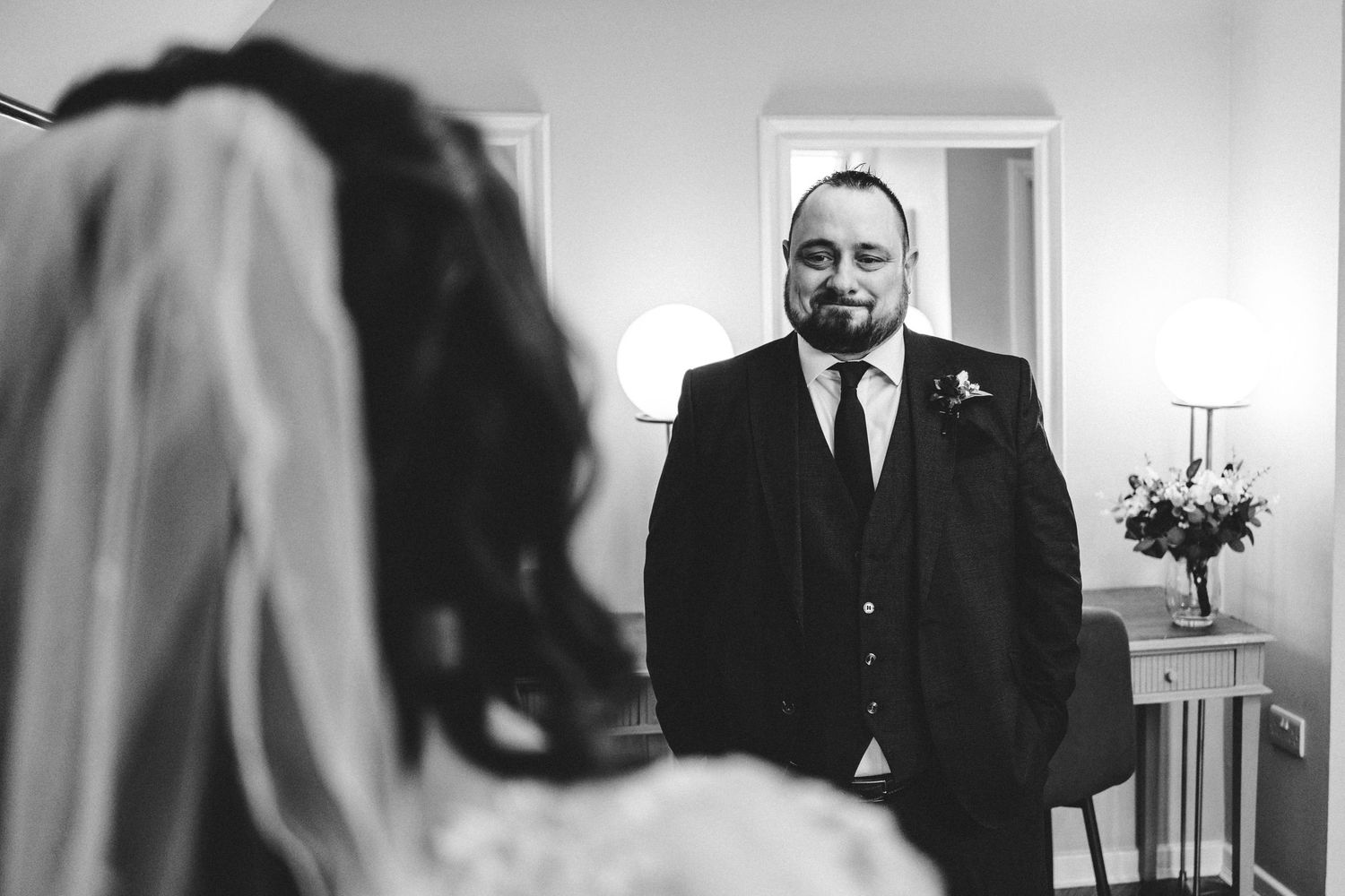 A wedding day moment captured through a mirror reflection in an indoor setting.