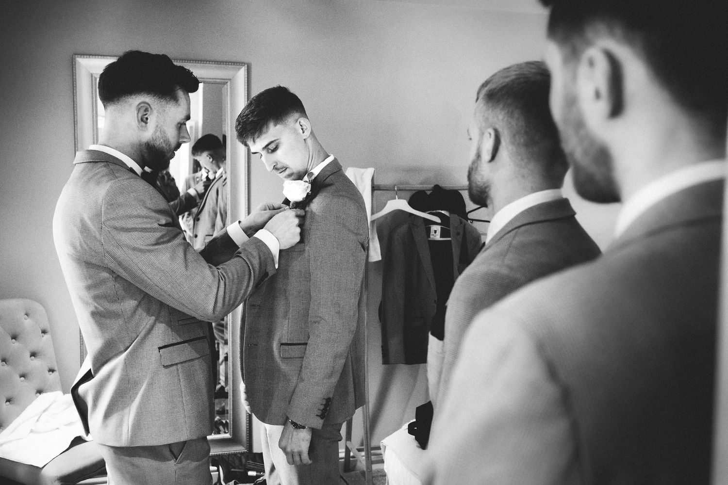 Candid black and white photo of wedding party members during pre-ceremony preparations.