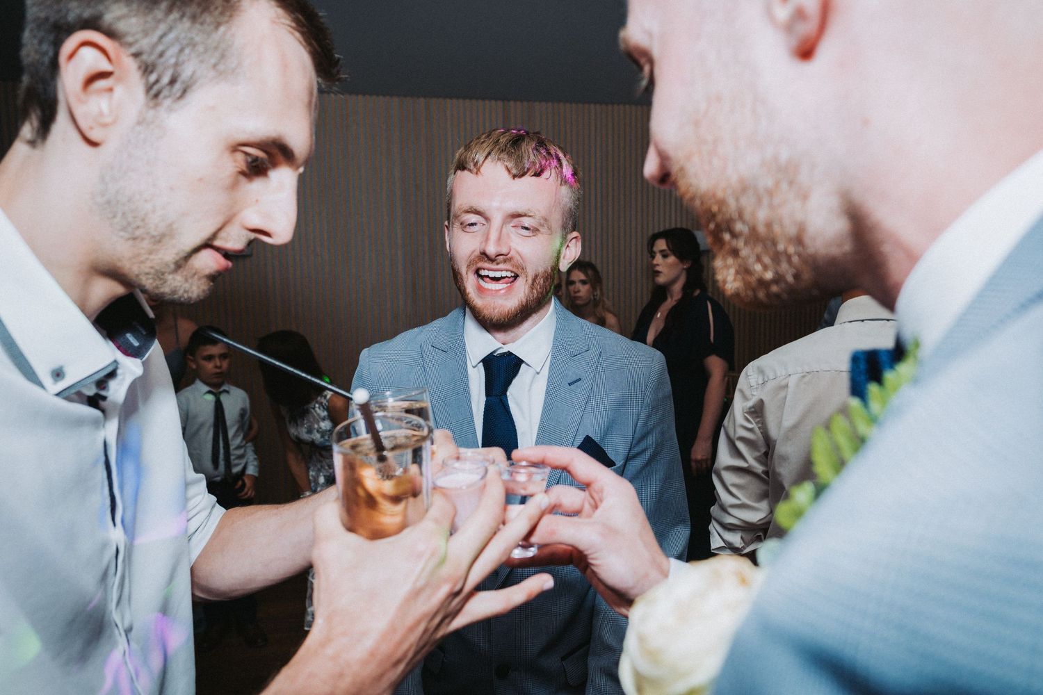 A group of guests sharing drinks and laughing together at an indoor celebration event.