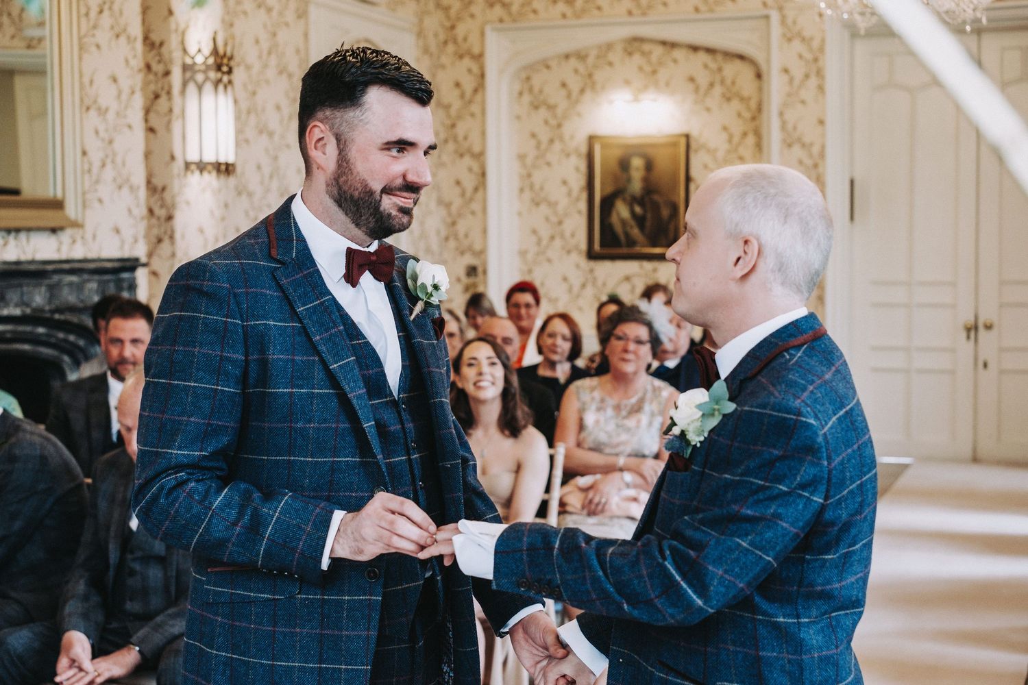 Two people share a joyful moment during a wedding ceremony in an ornate room.