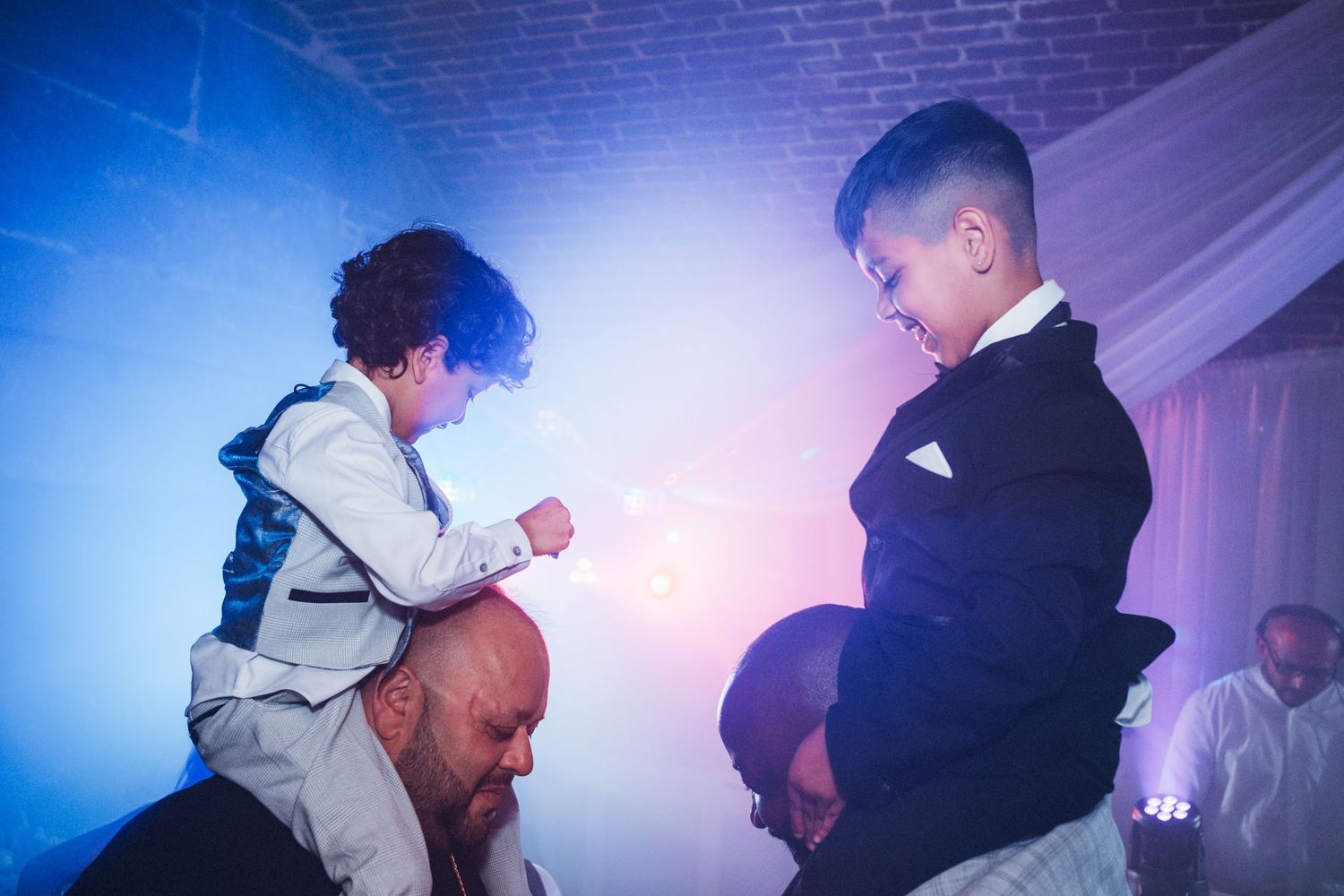 Silhouettes of people dancing at a wedding reception with dramatic blue and purple lighting.