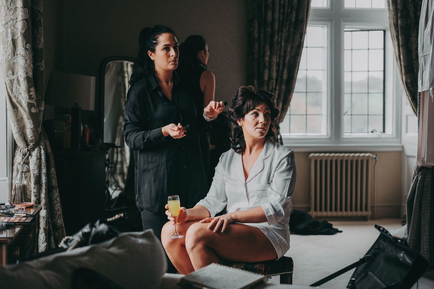 Two people in a vintage-style room during wedding preparation.